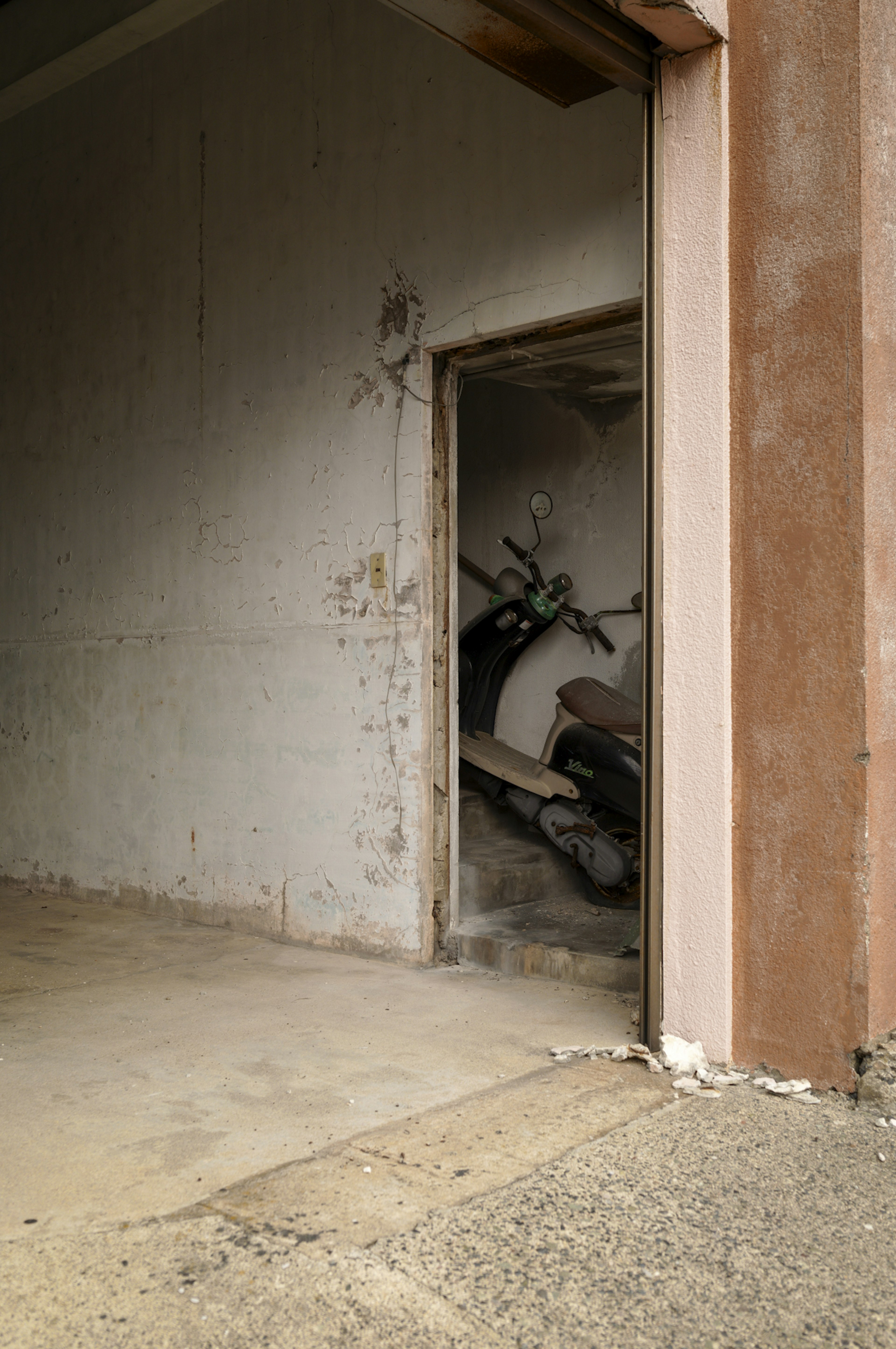 An open door reveals a motorcycle in a dilapidated space