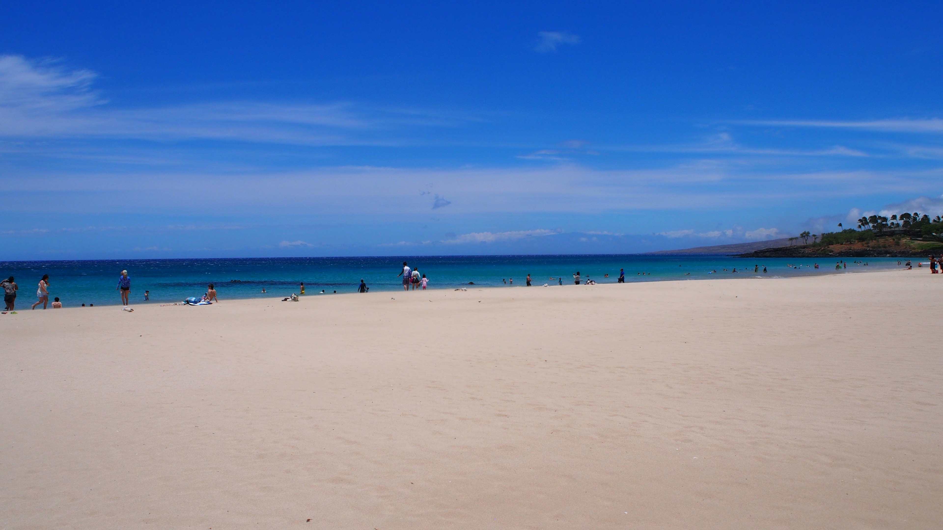 Personas disfrutando de una playa con agua azul y arena blanca