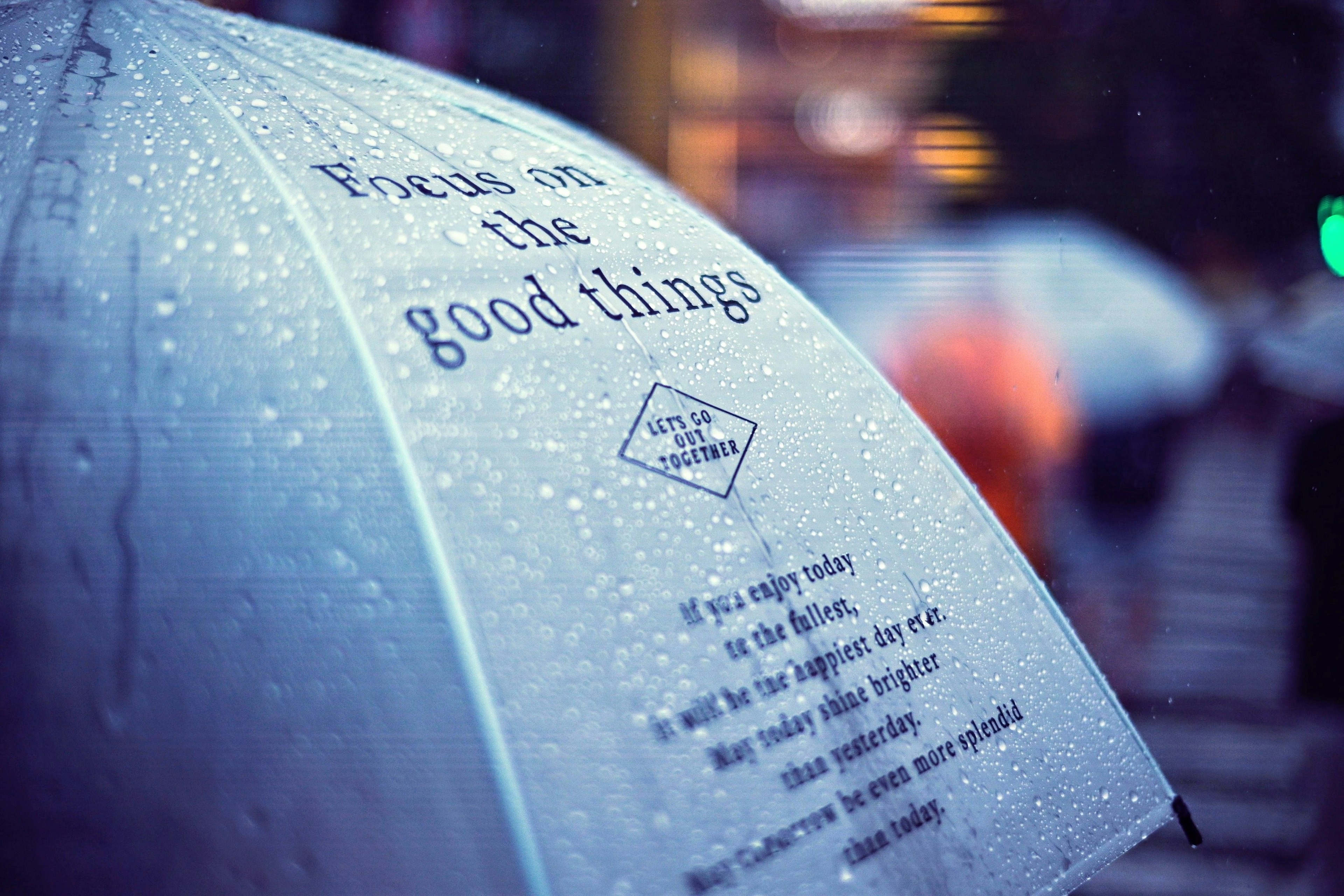 A close-up of a clear umbrella with water droplets and a motivational message