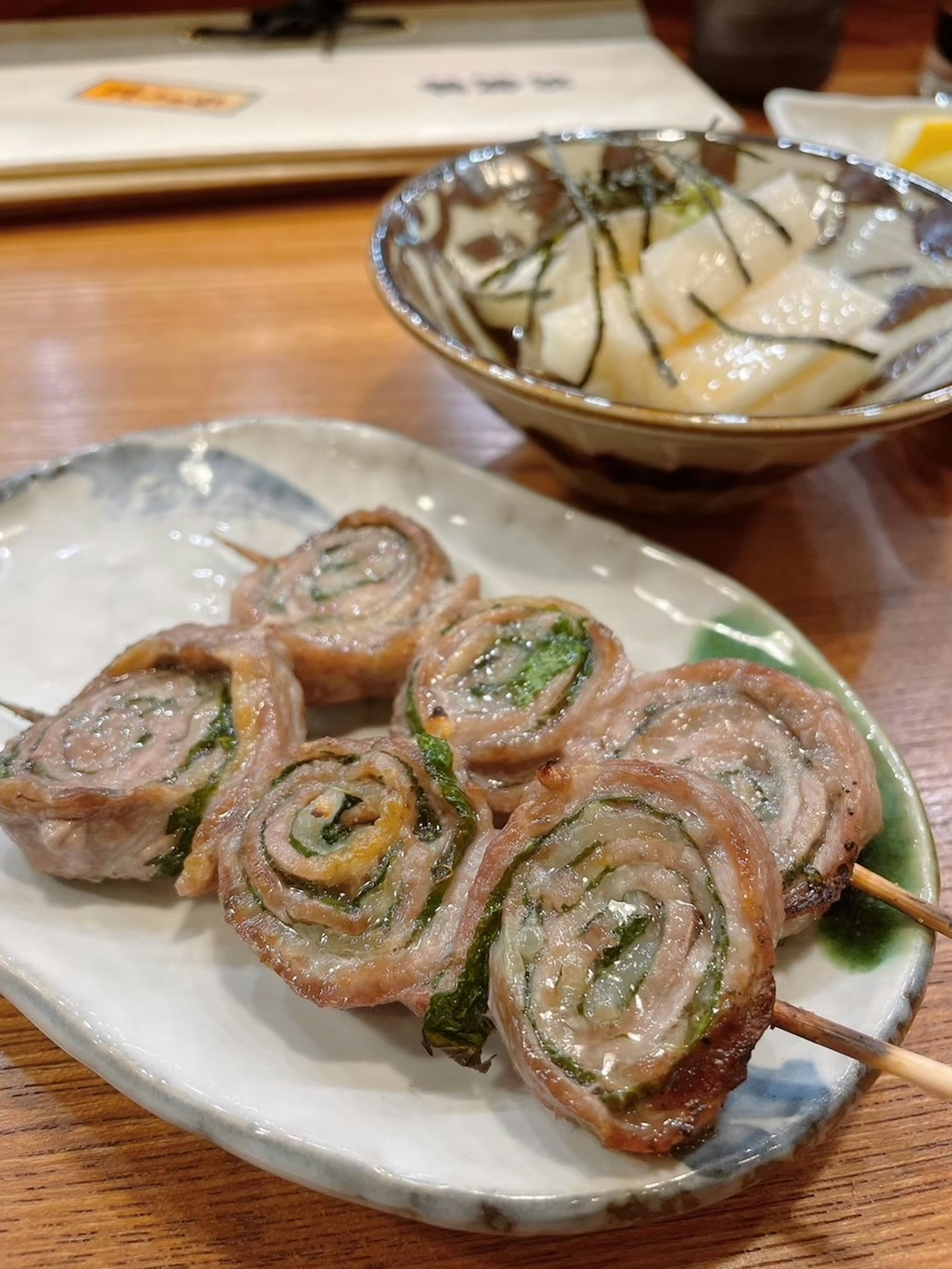 Involtini di carne grigliati con verdure su un piatto e un'insalata giapponese a lato