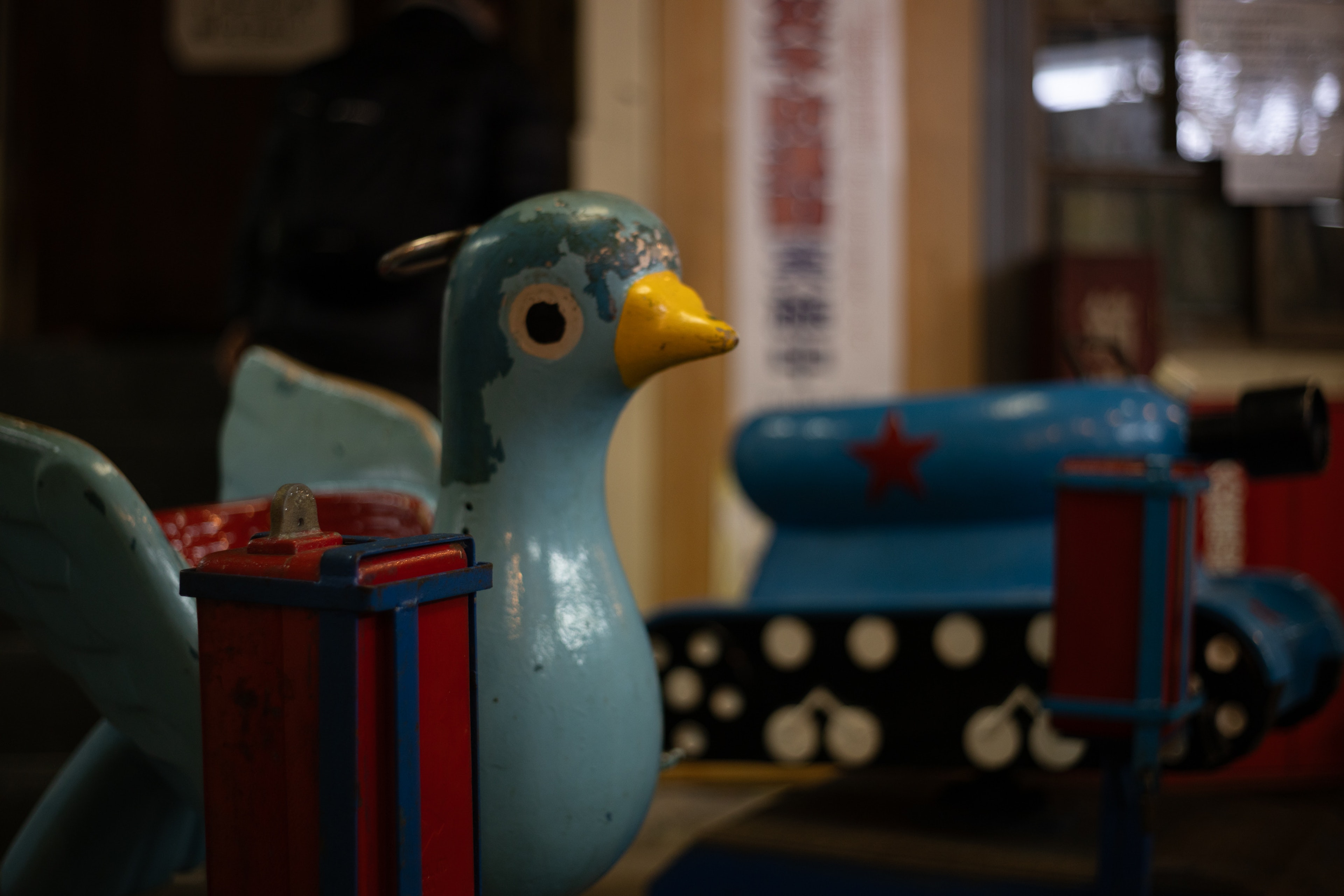 Indoor scene featuring a blue bird sculpture and colorful toy tank