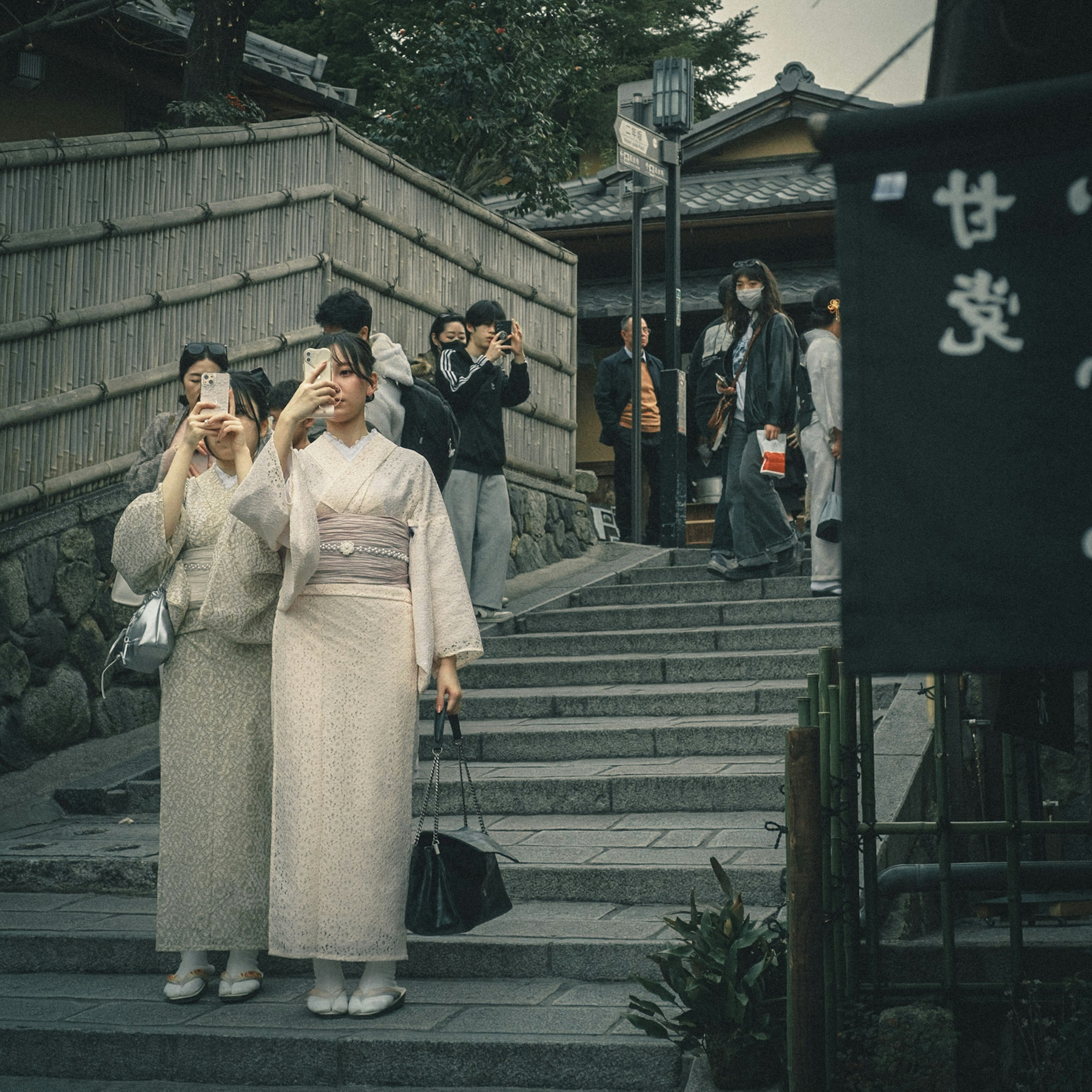 Women in kimonos taking photos on a staircase