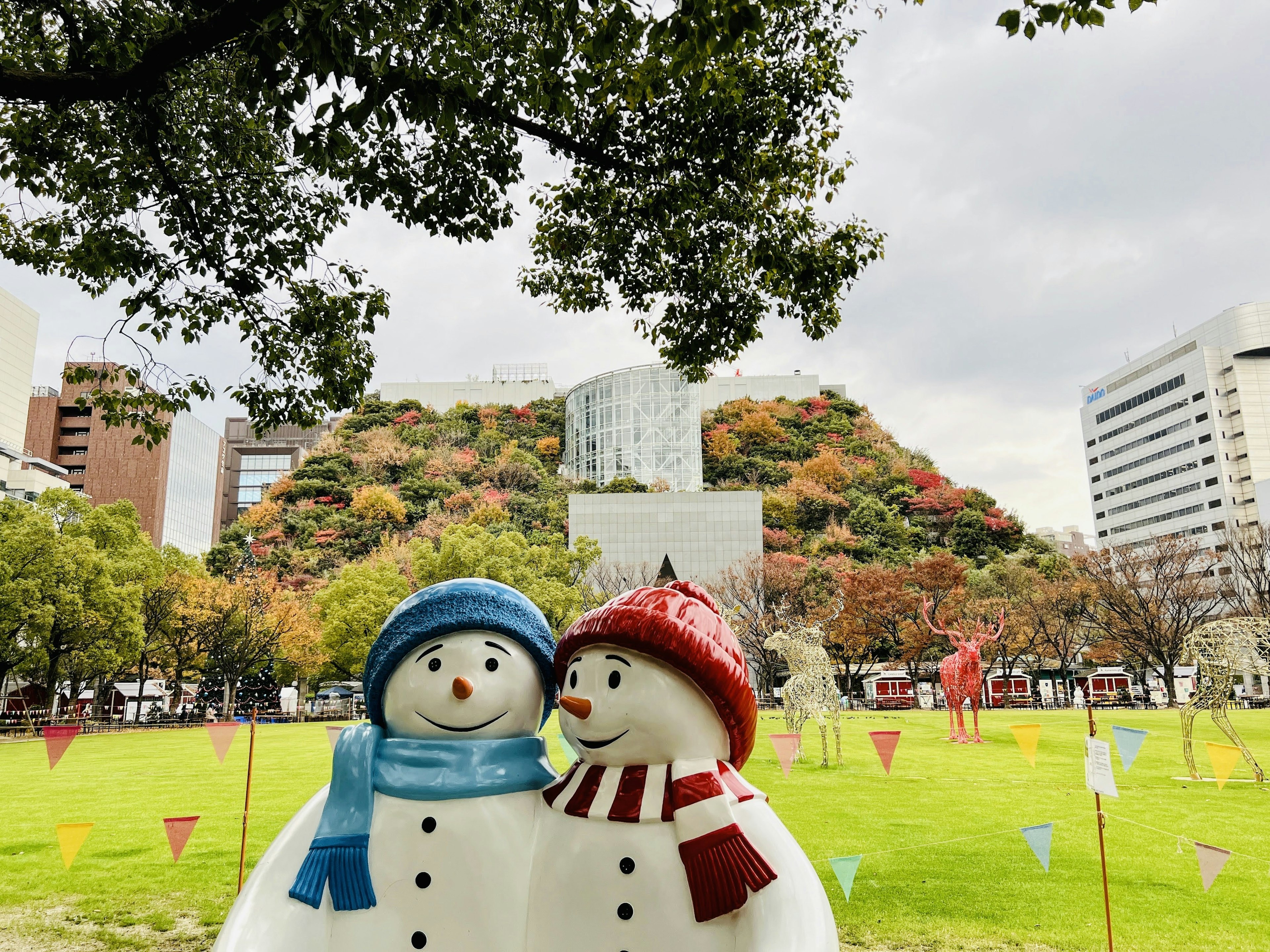 Snowmen in a park with colorful trees in the background