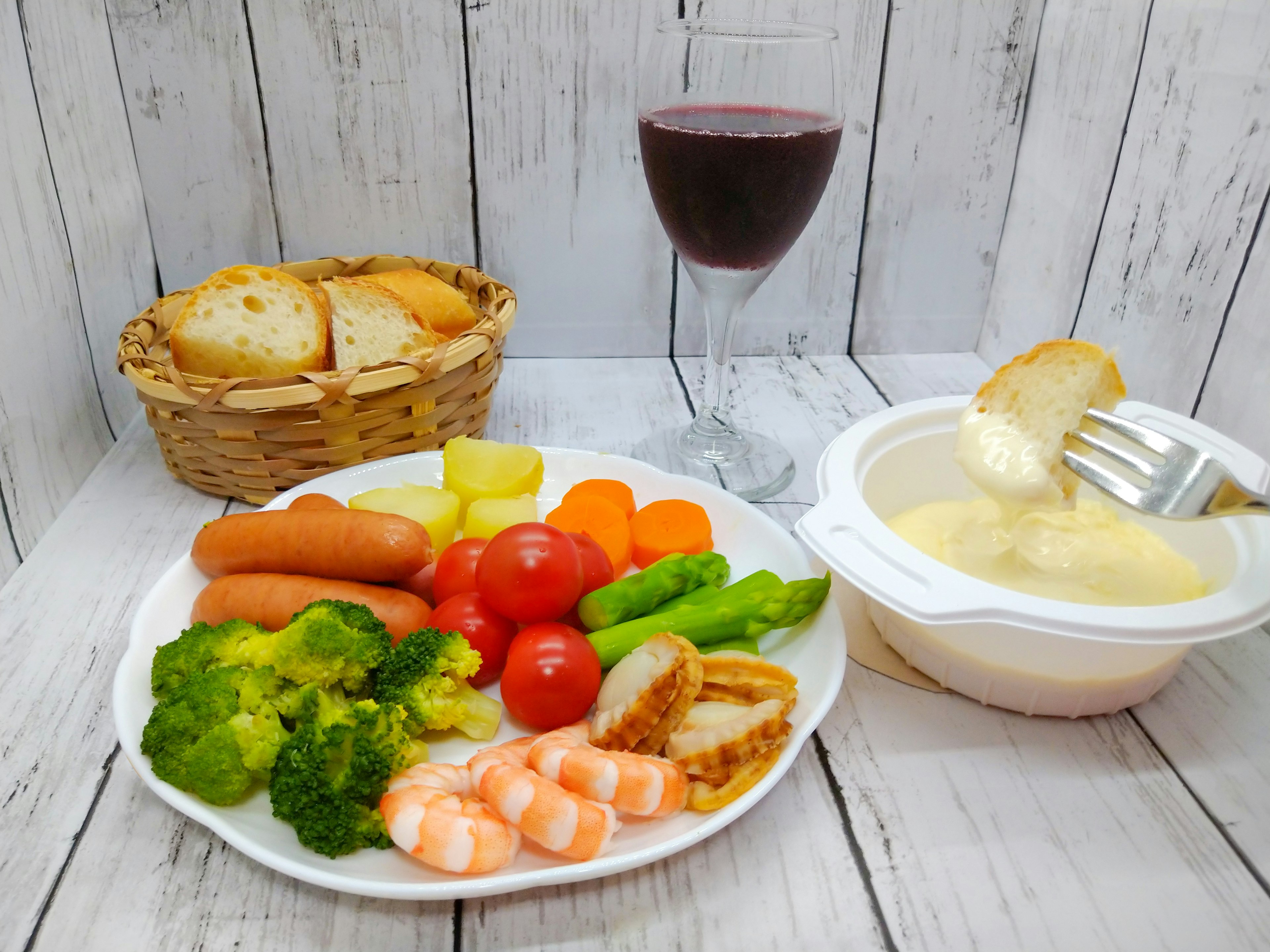 A plate of colorful vegetables and seafood with a glass of red wine in the background