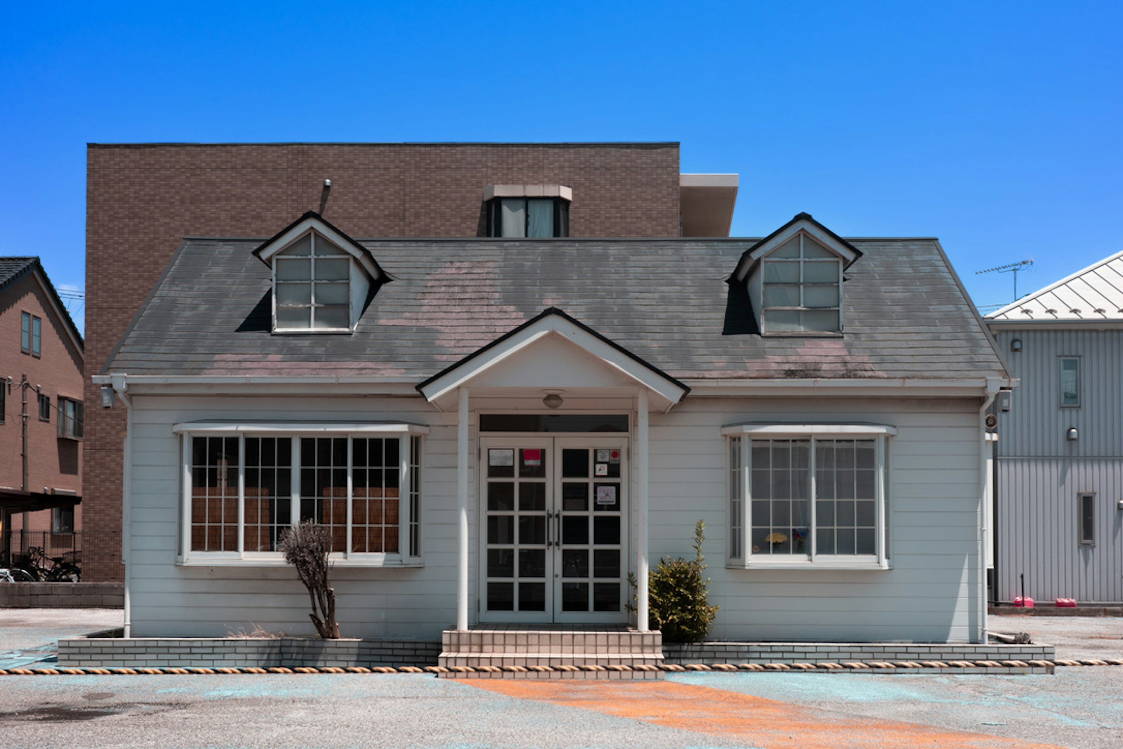 Charming house exterior under a blue sky with distinctive roof and large windows