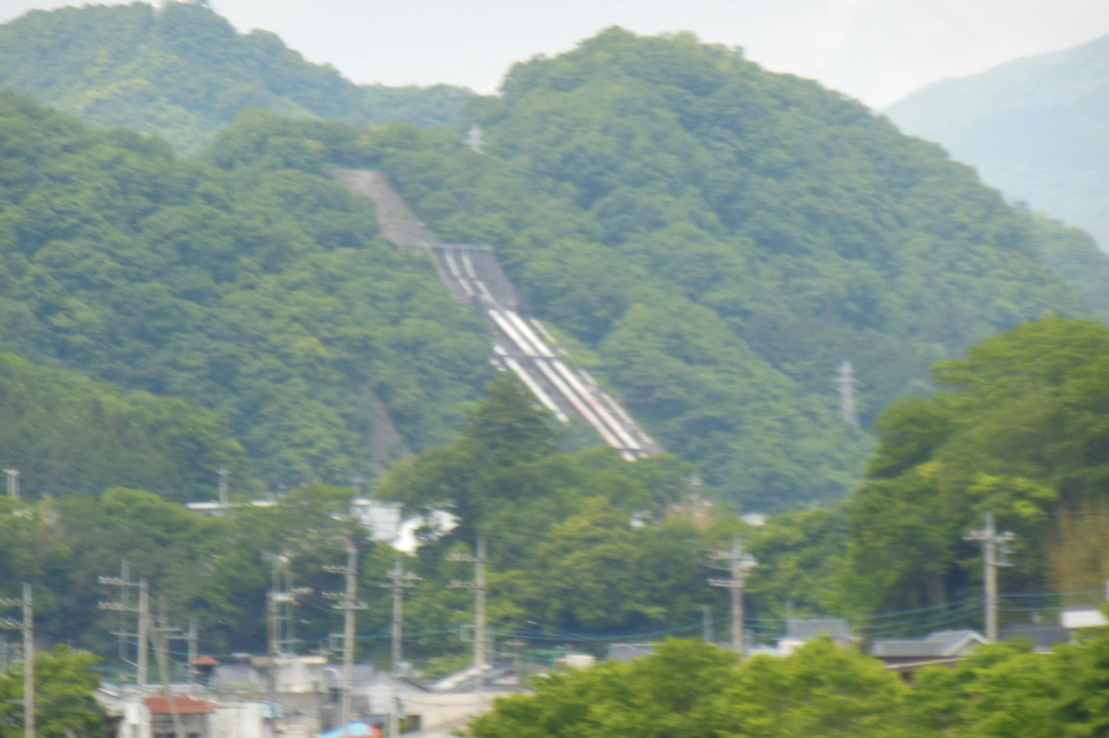 A view of a slide surrounded by mountains and greenery