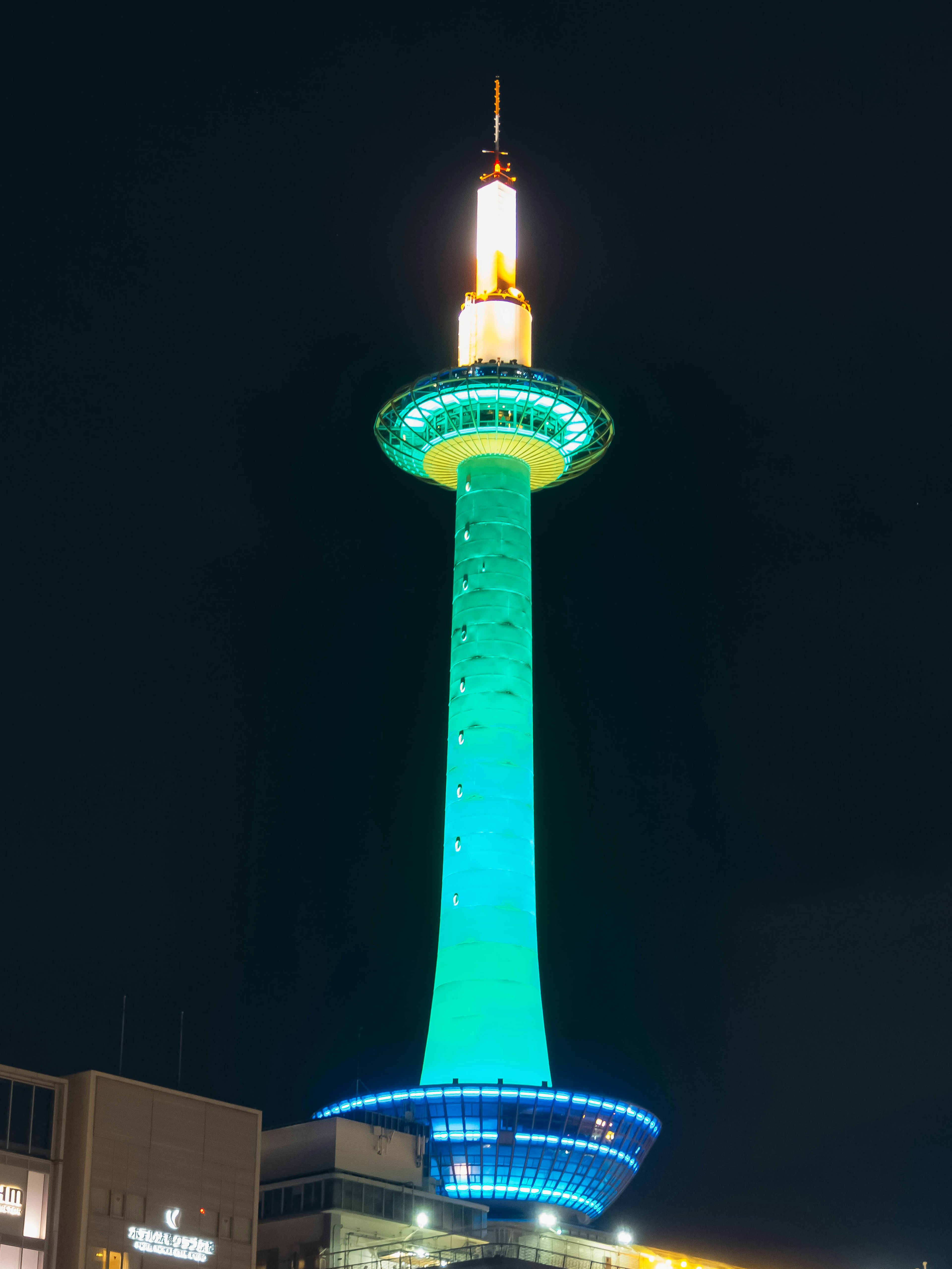 Kyoto Tower illuminated in vibrant green and blue at night