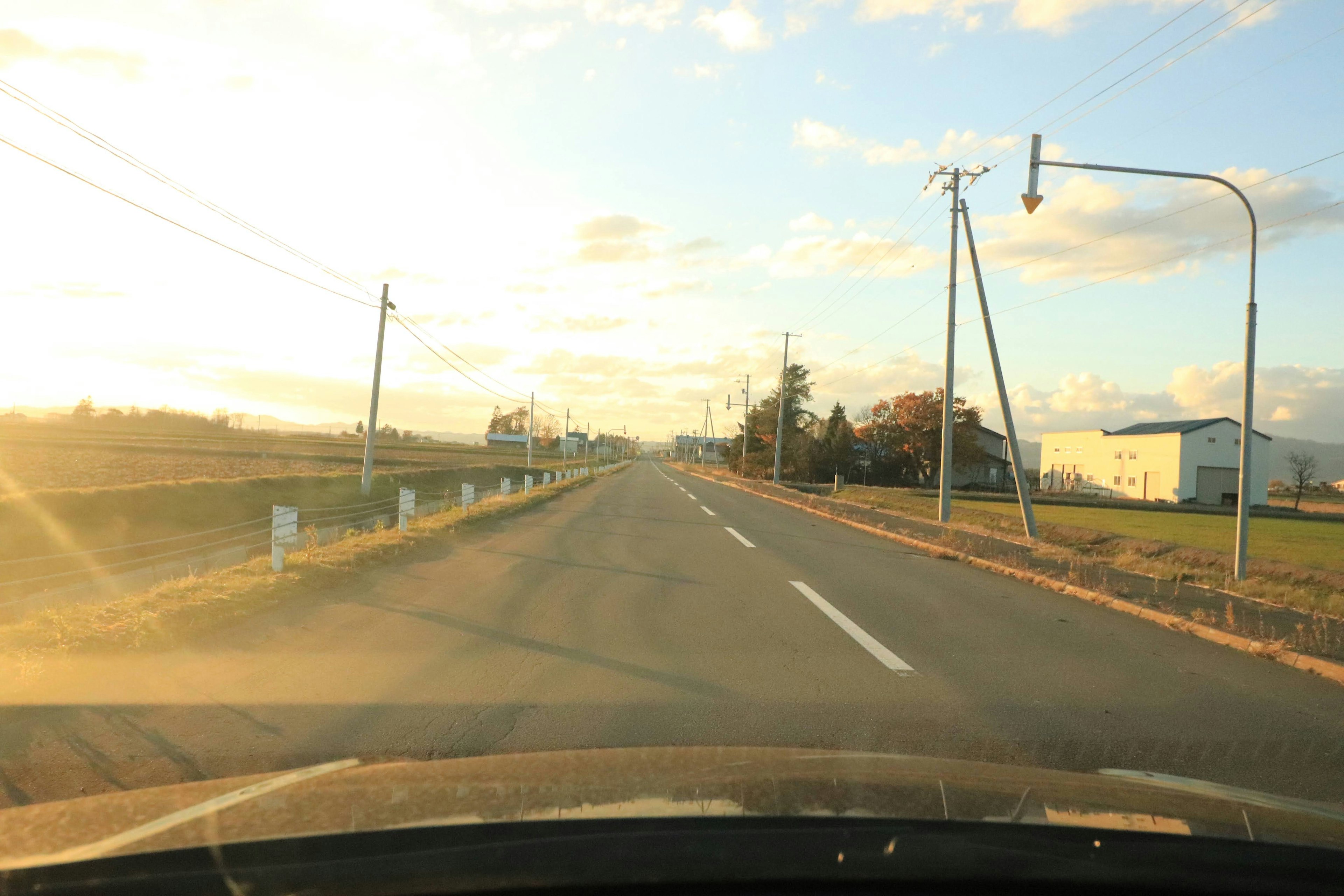 Countryside road at sunset viewed through car windshield