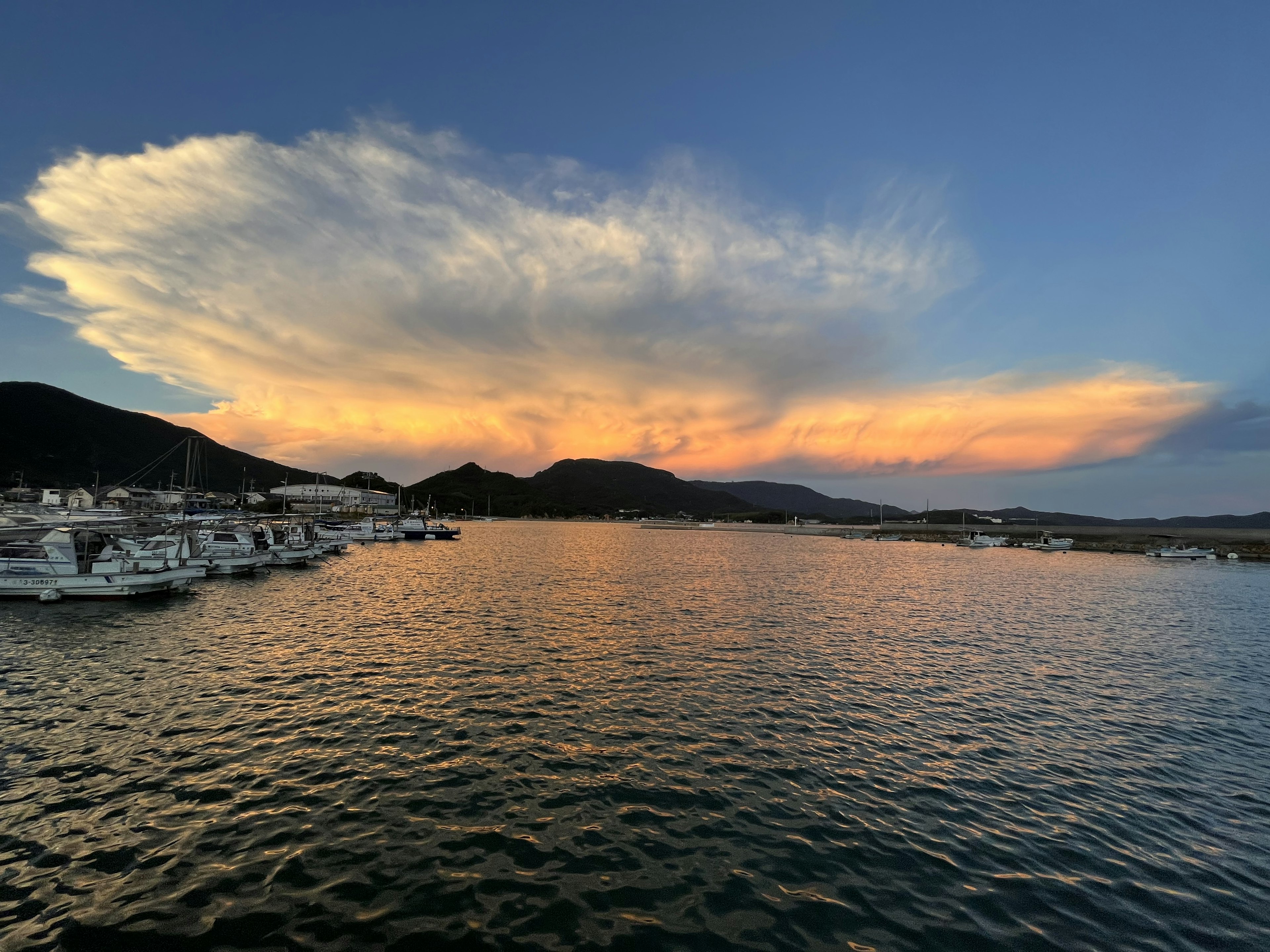 Sunset over a calm sea with boats in the harbor