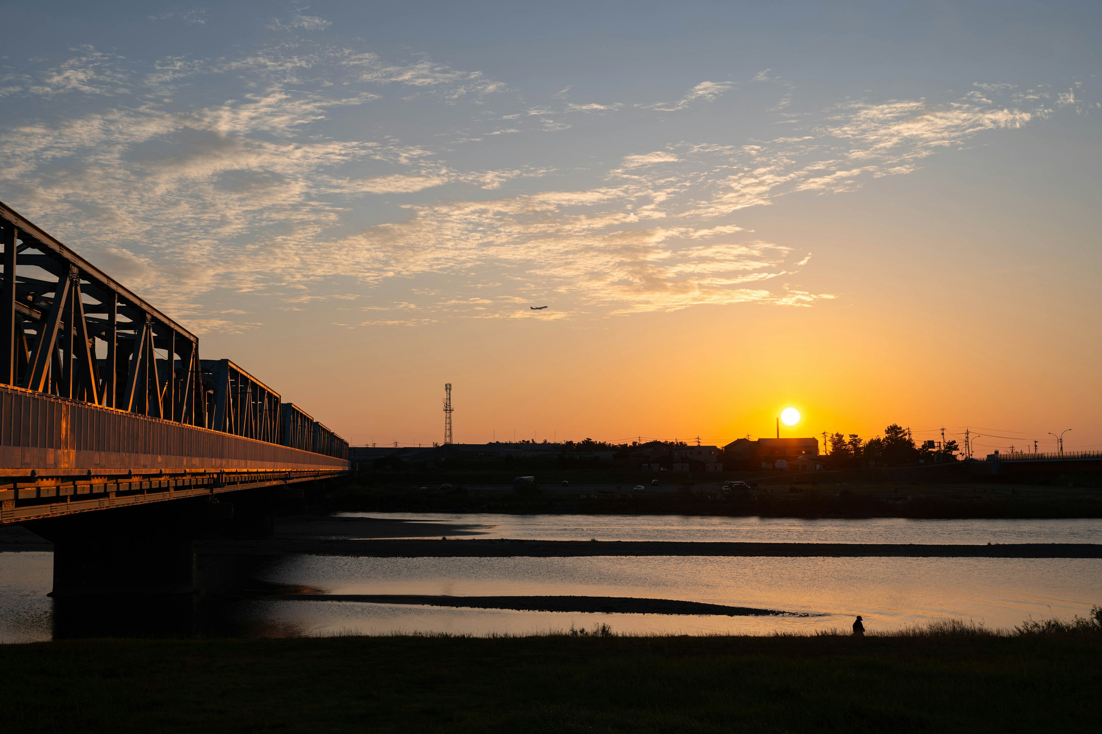 Eine malerische Aussicht auf eine Eisenbahnbrücke bei Sonnenuntergang mit Reflexionen im Wasser