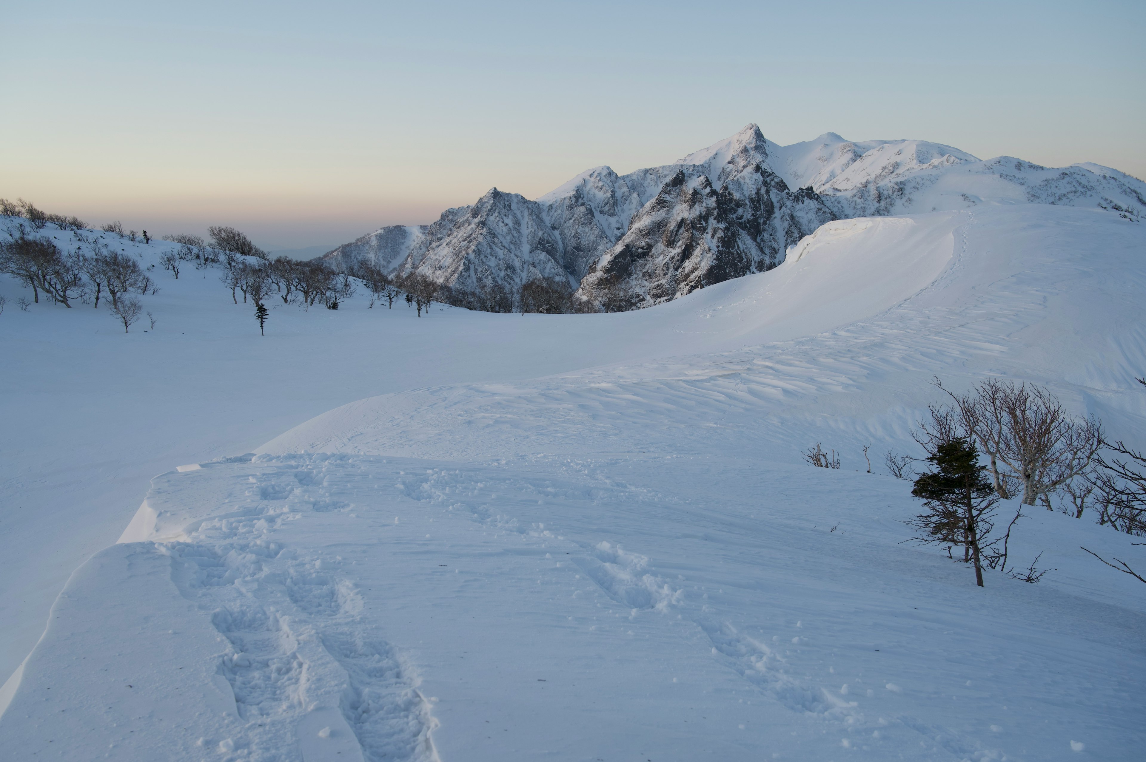 Paisaje montañoso cubierto de nieve con huellas visibles