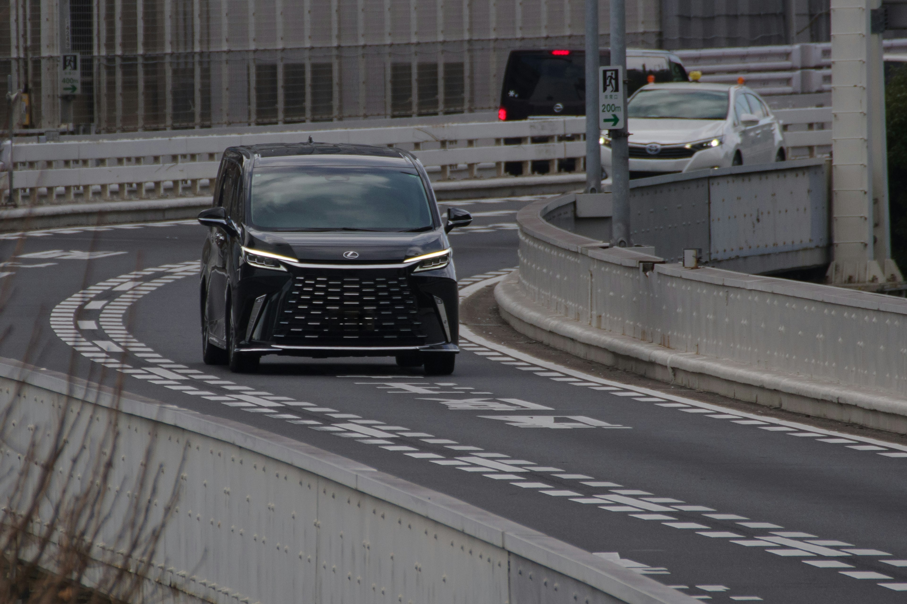 黒いミニバンがカーブを曲がっている都市の道路