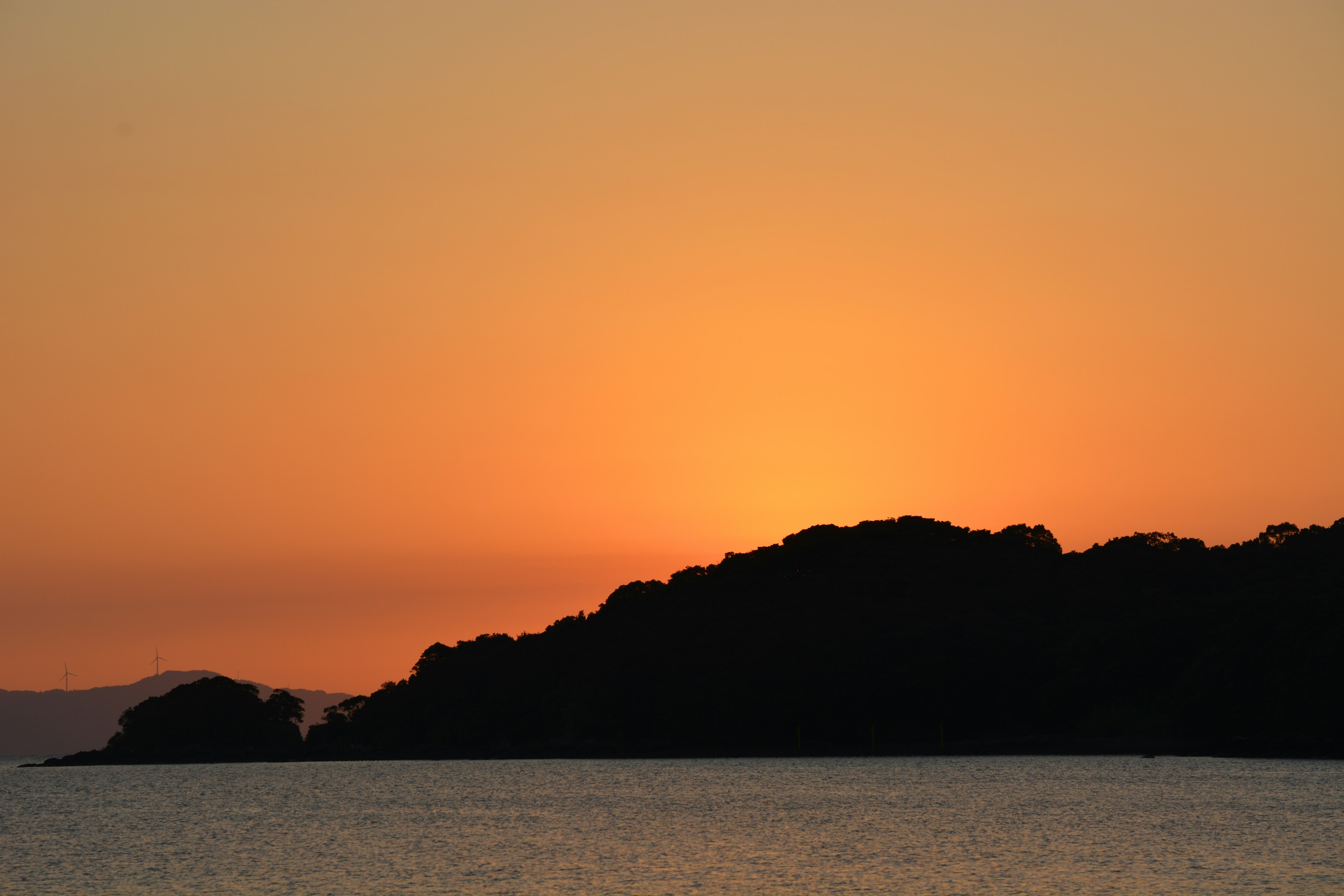 Silhouette of a coastline with a sunset over the ocean