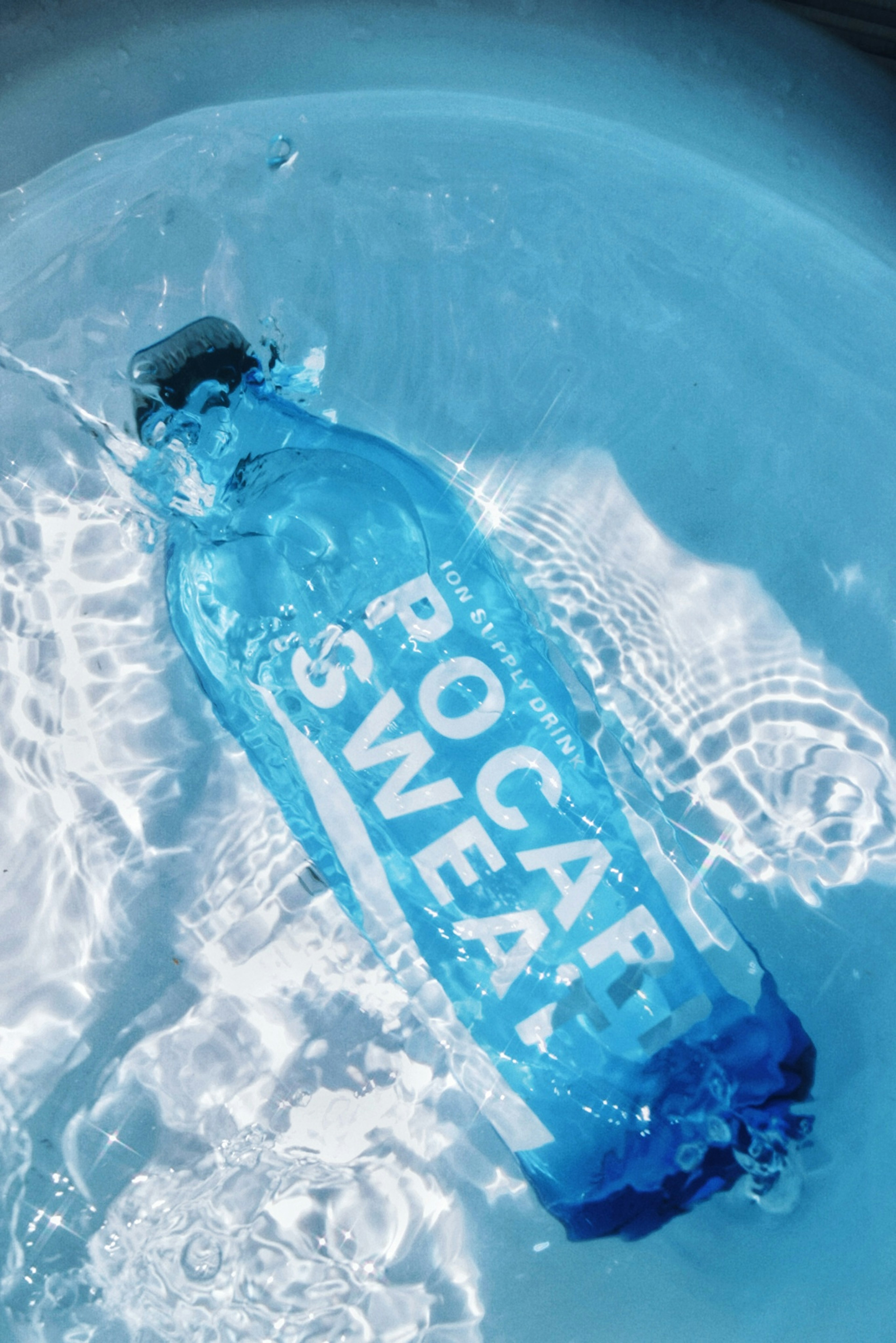 A blue bottle labeled ROCAP SWEAT floating in clear water