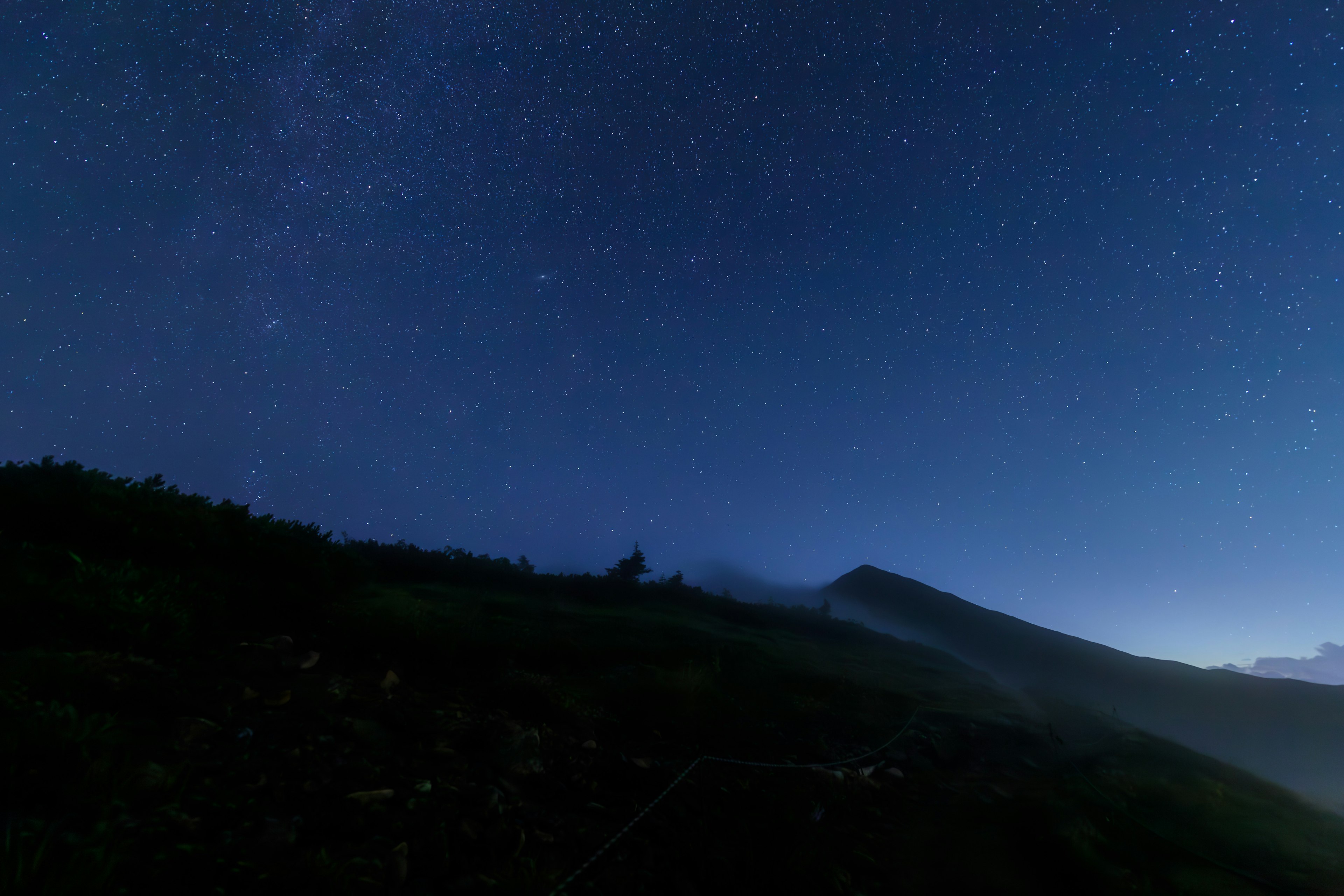 Ciel étoilé au-dessus d'un paysage montagneux avec un horizon sombre