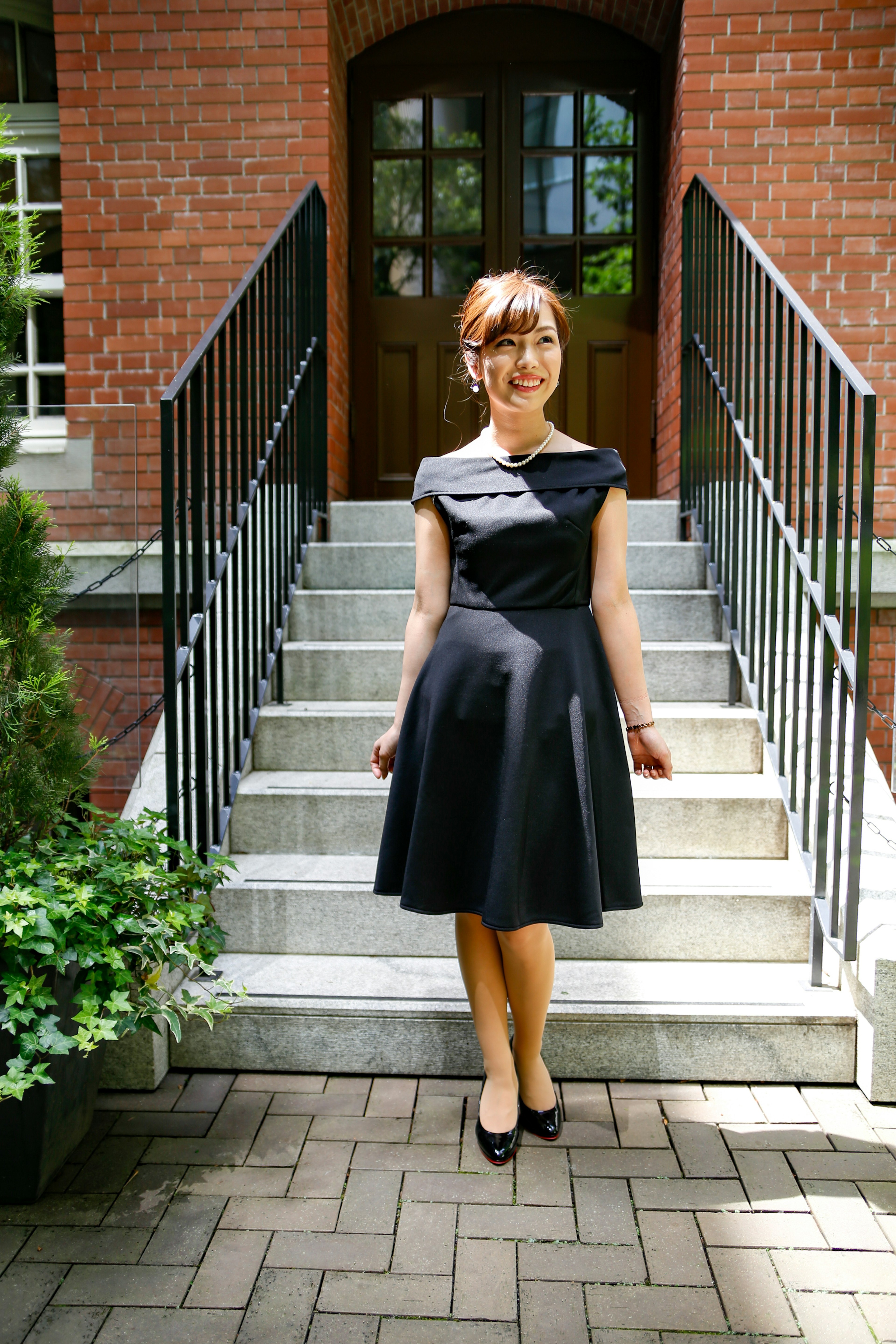 Woman in a black dress standing in front of stairs