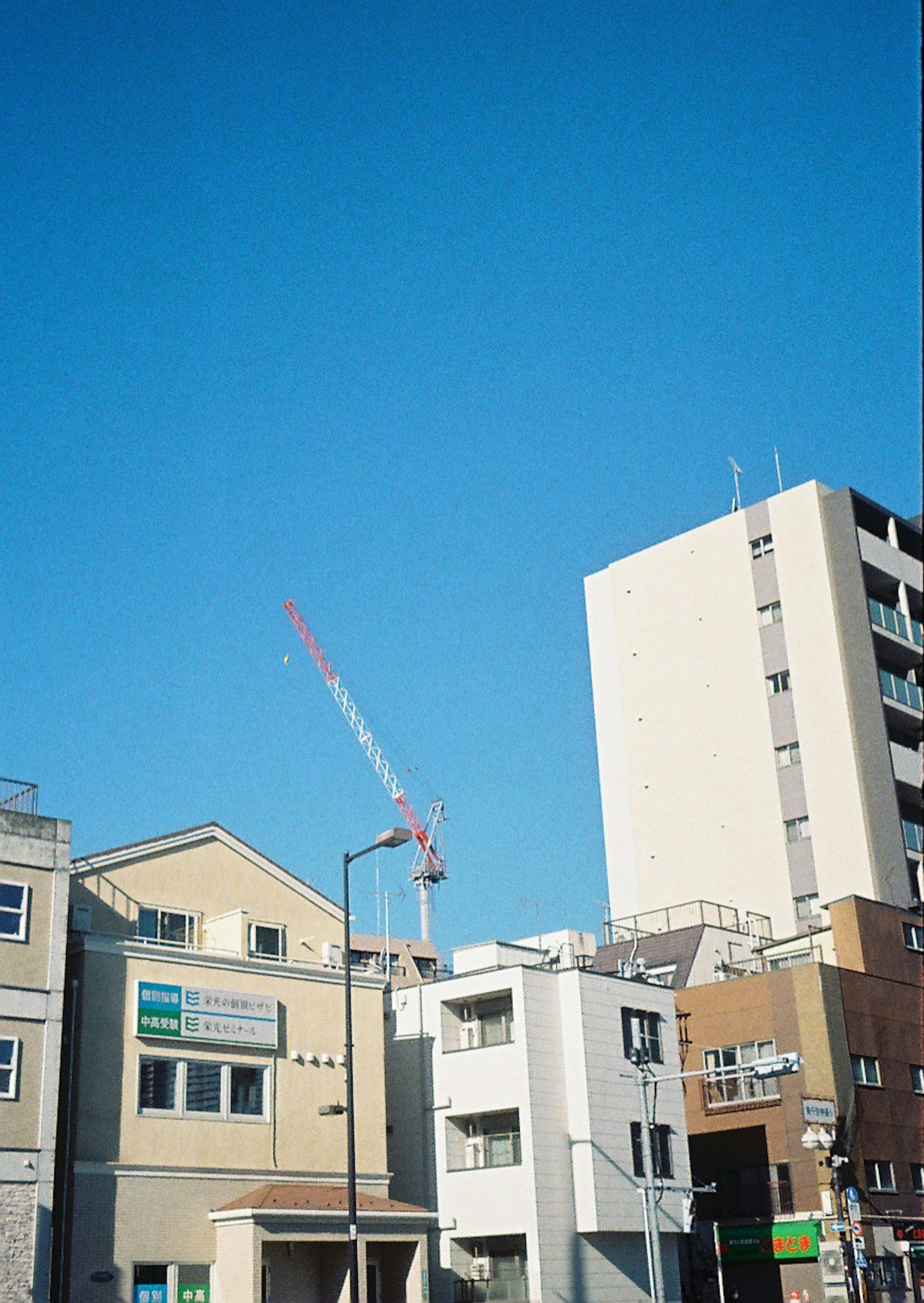 Stadtansicht mit Gebäuden und einem Kran unter blauem Himmel