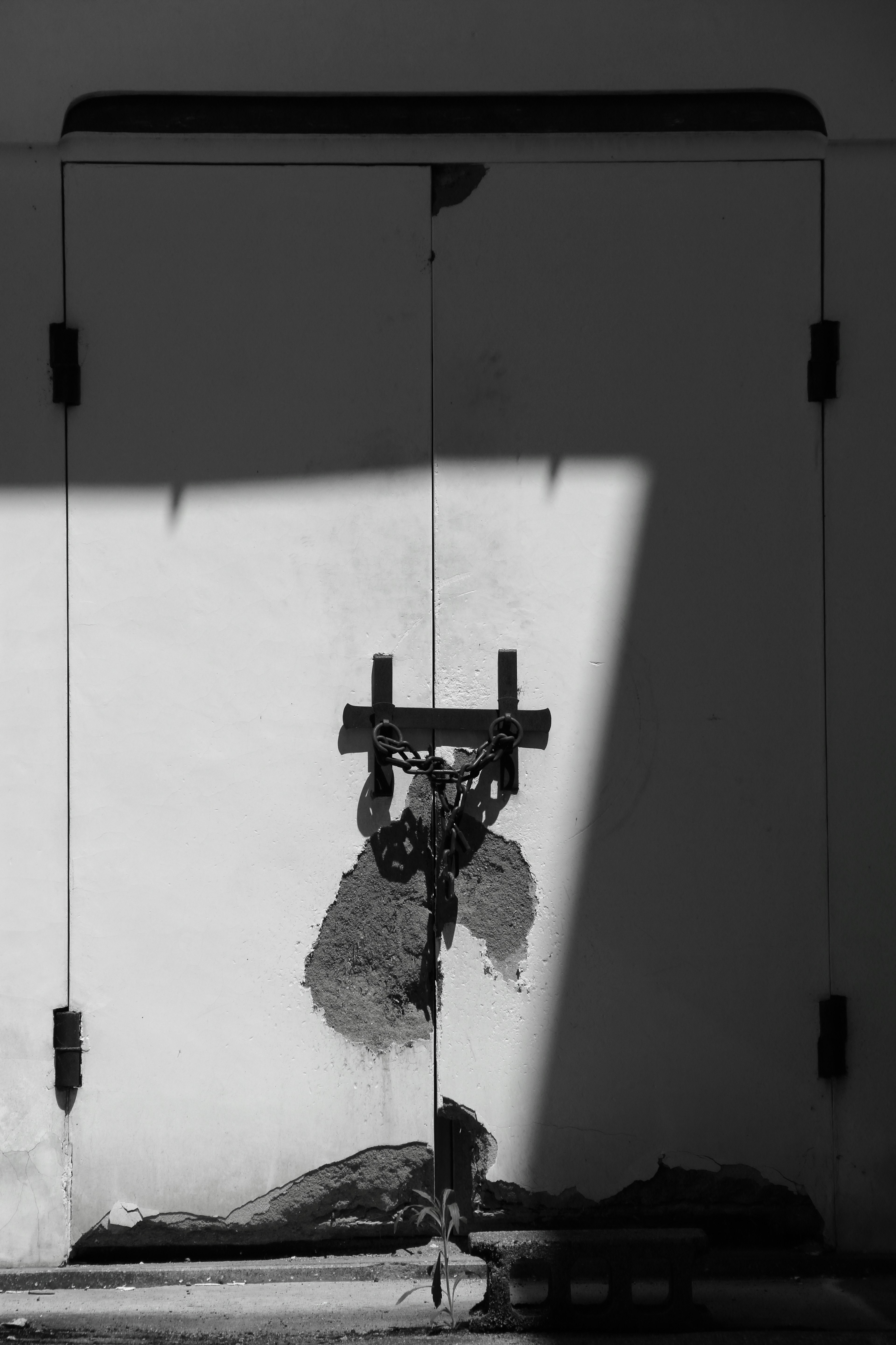 Black and white image of a locked door with shadows cast on it