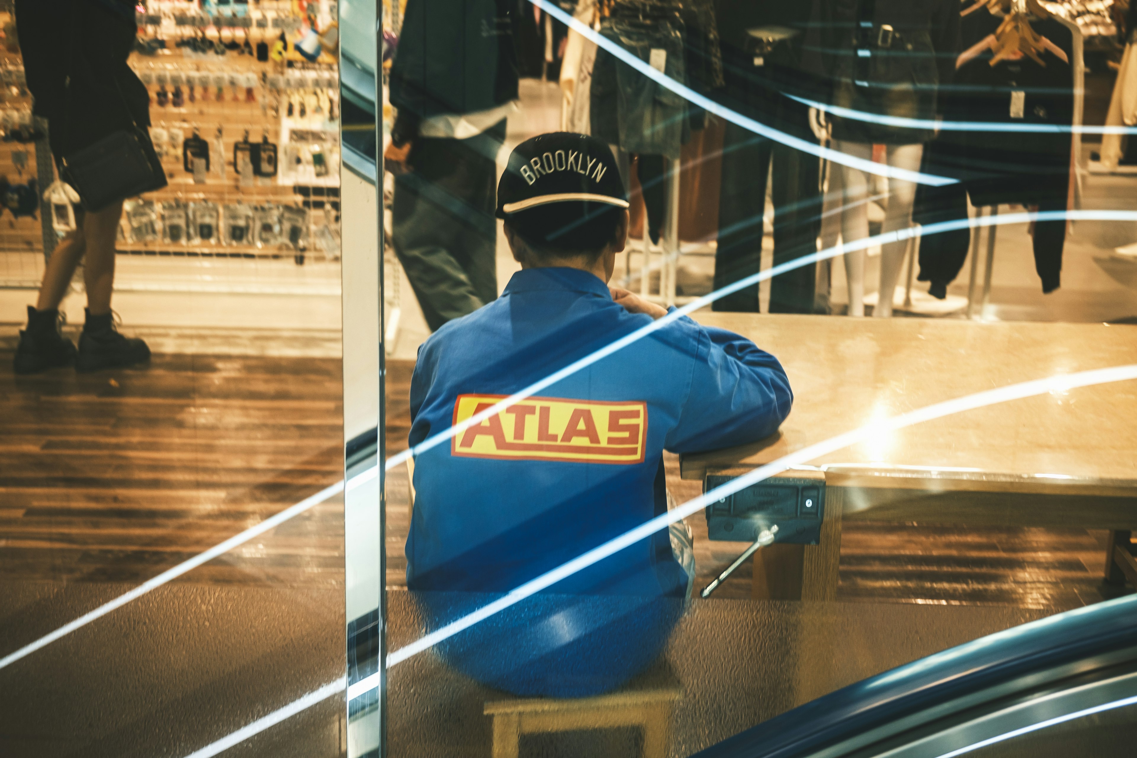 Un homme assis de dos portant une veste bleue avec le mot ATLAS