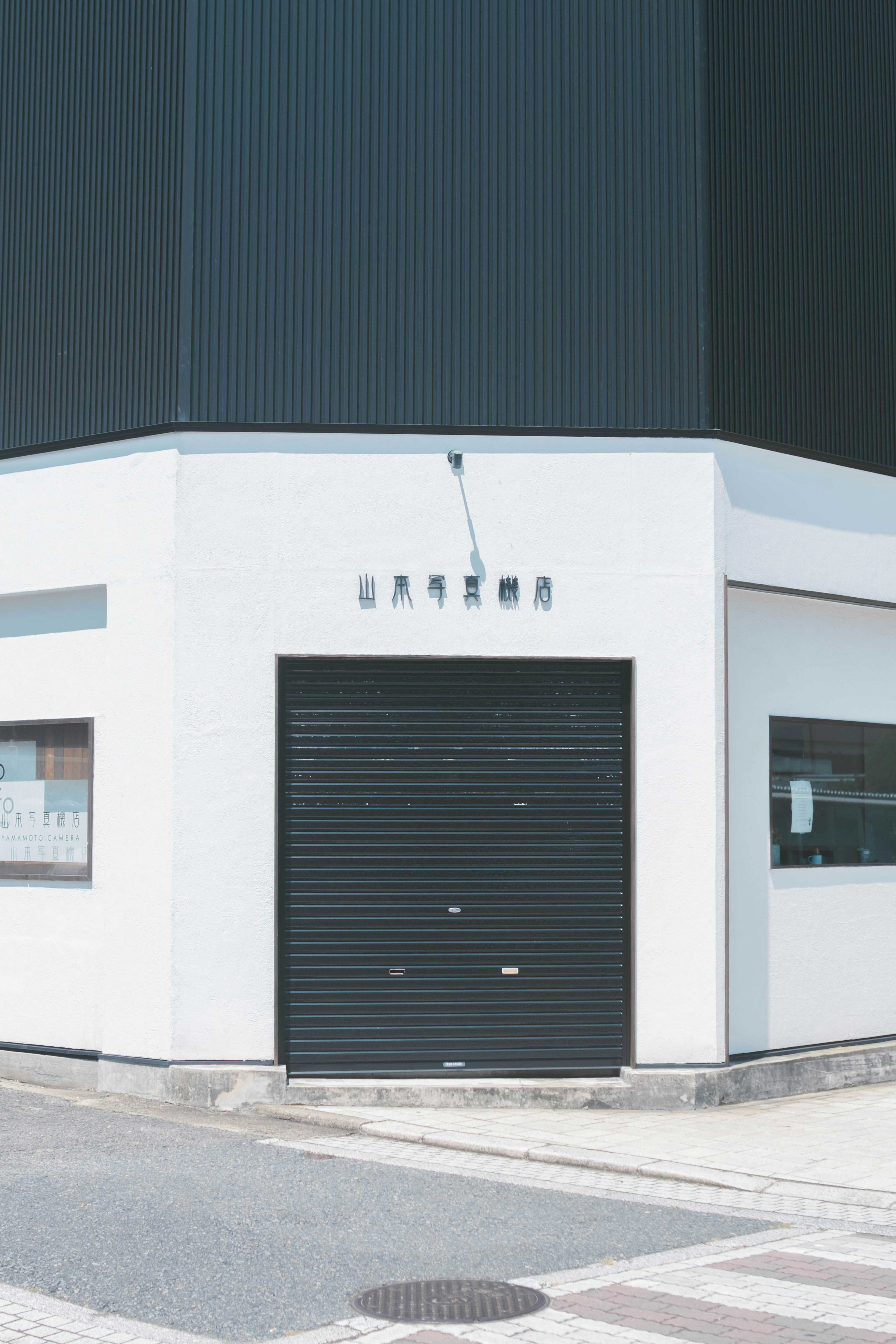 Esquina de un edificio blanco con una puerta de persiana negra