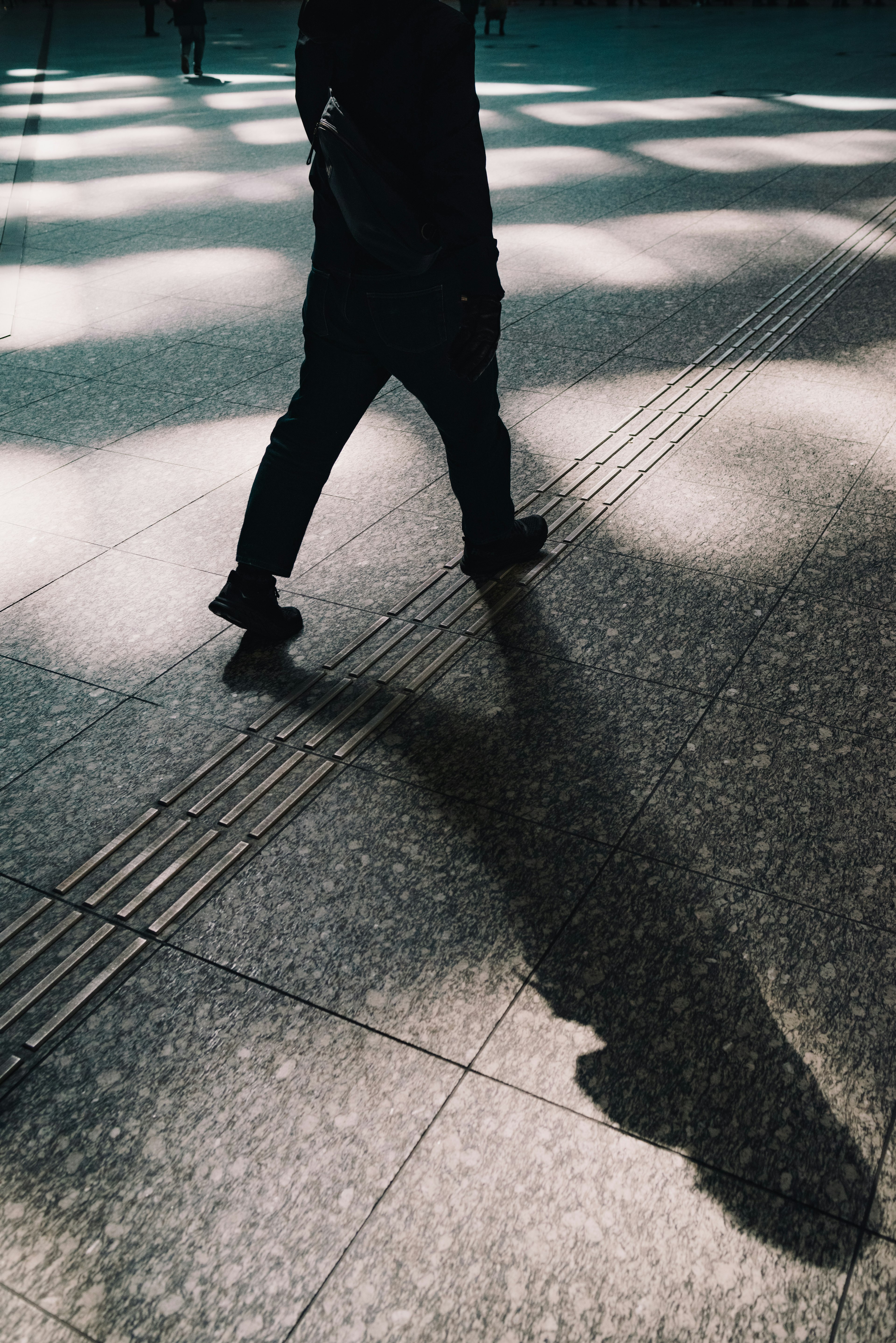 Silhouette di un pedone che cammina con un'ombra sul pavimento