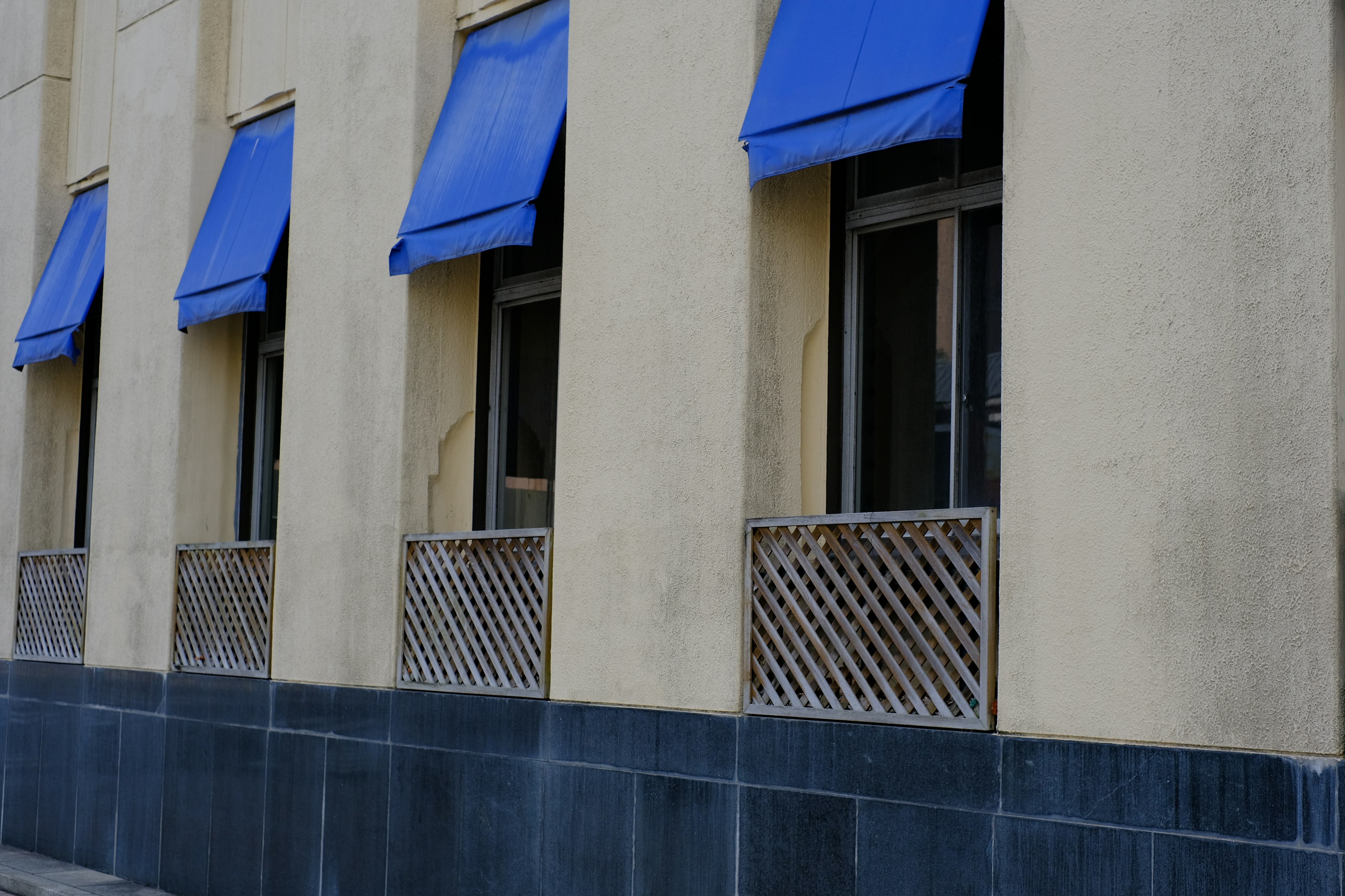 Fachada de un edificio con toldos azules sobre las ventanas