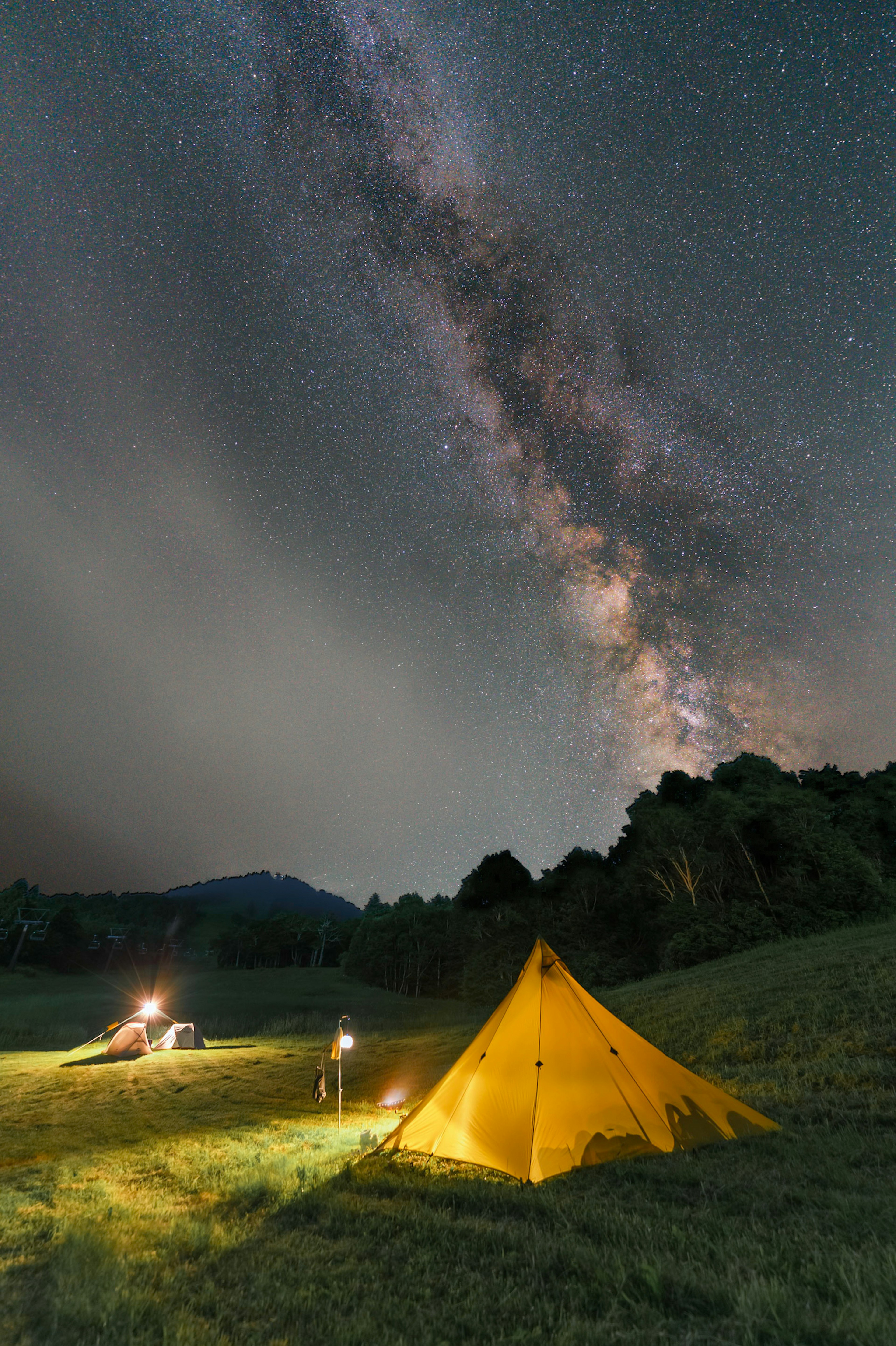 星空の下でキャンプをする人々と黄色いテント