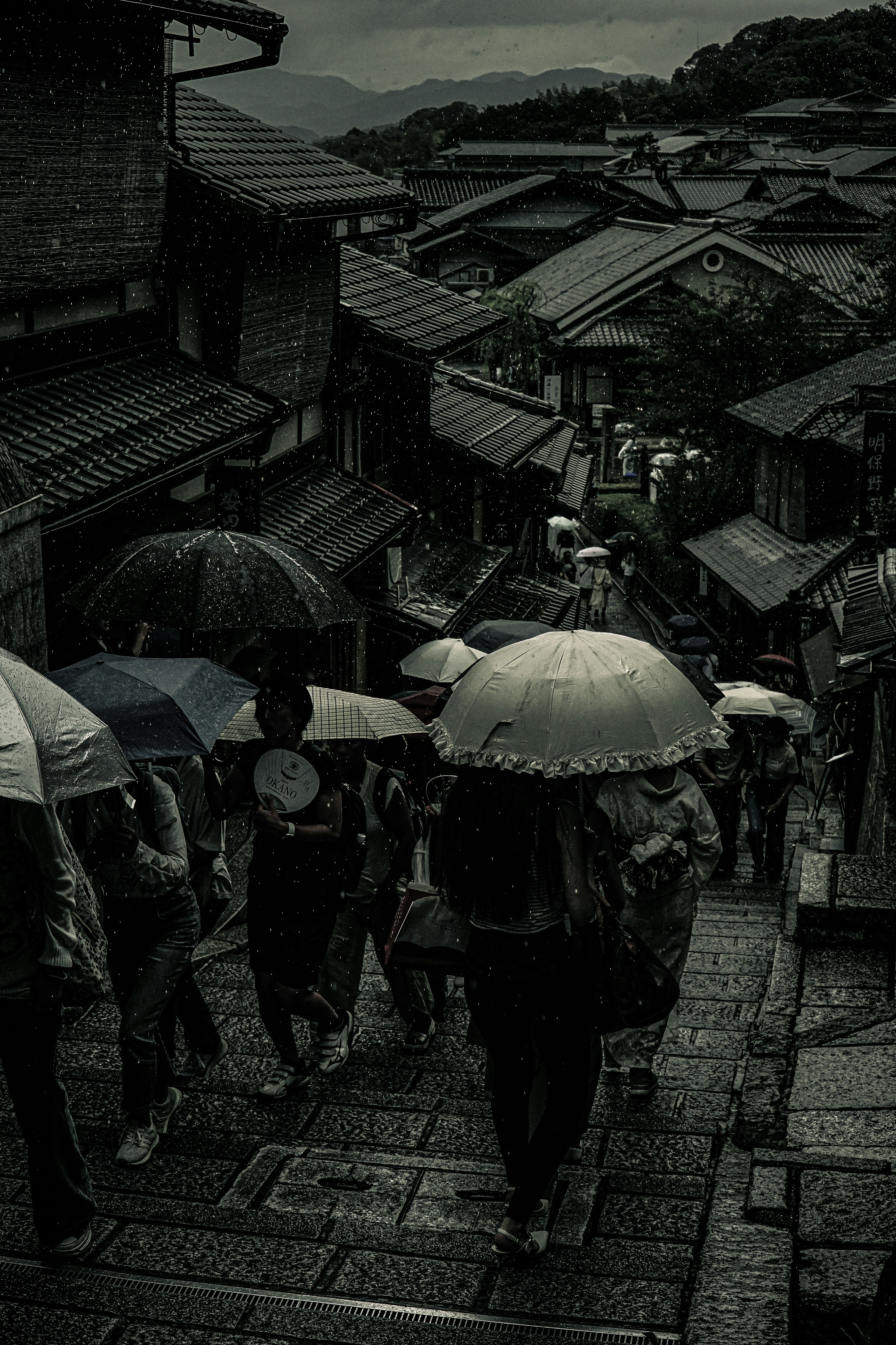 People walking in the rain holding umbrellas in an old street