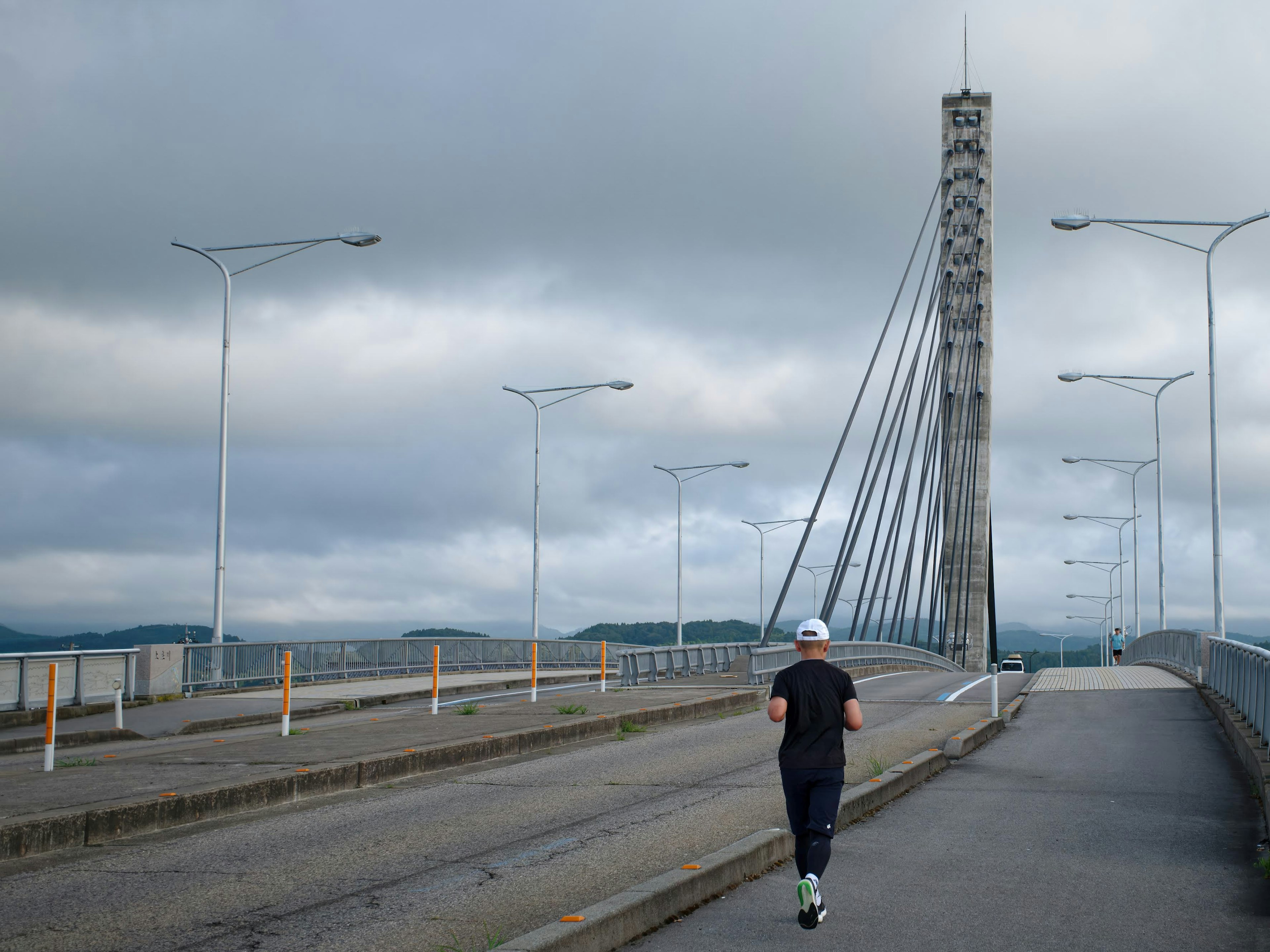 Pria berlari di jembatan di bawah langit mendung