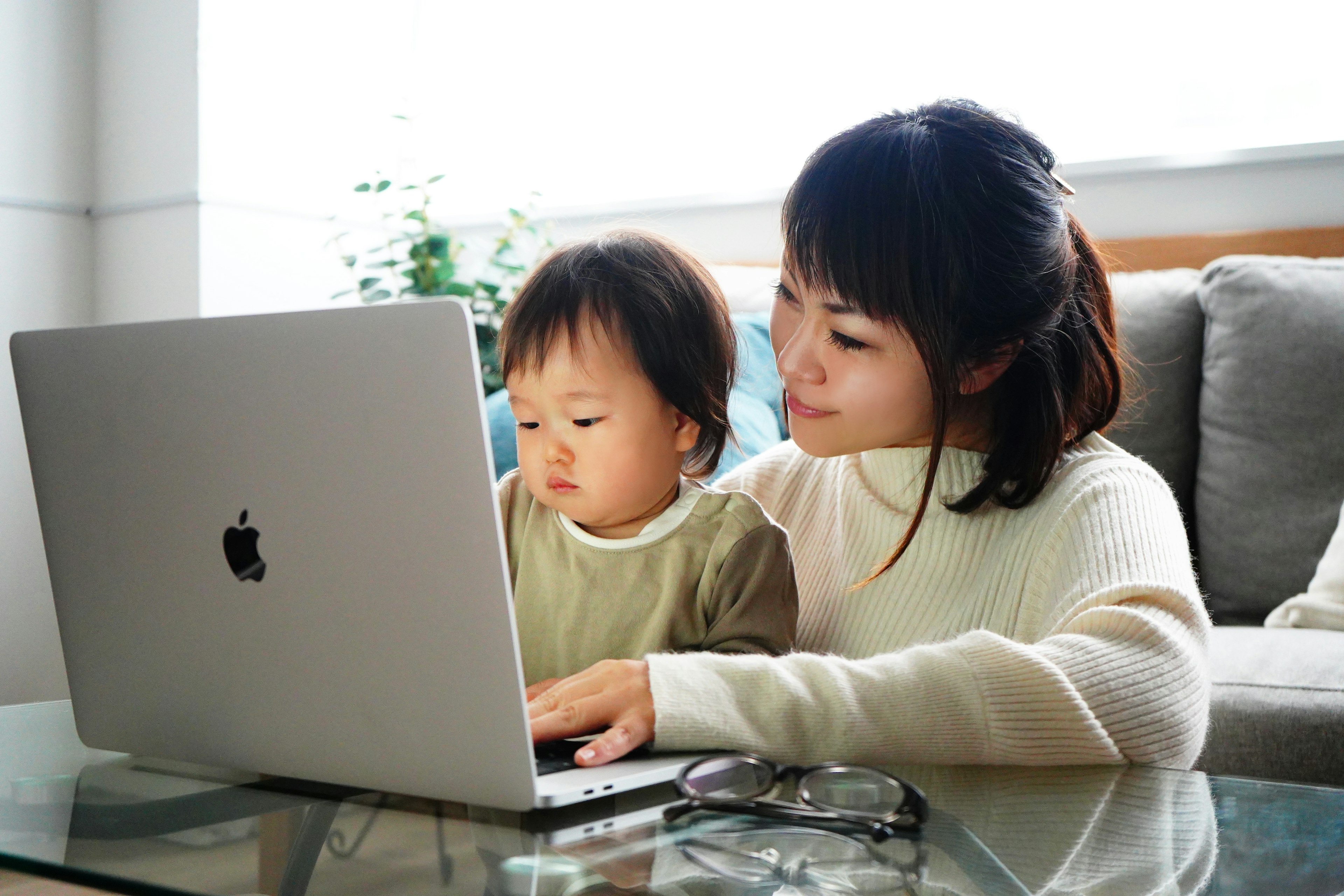 A mother and toddler engaged with a laptop in a cozy indoor setting