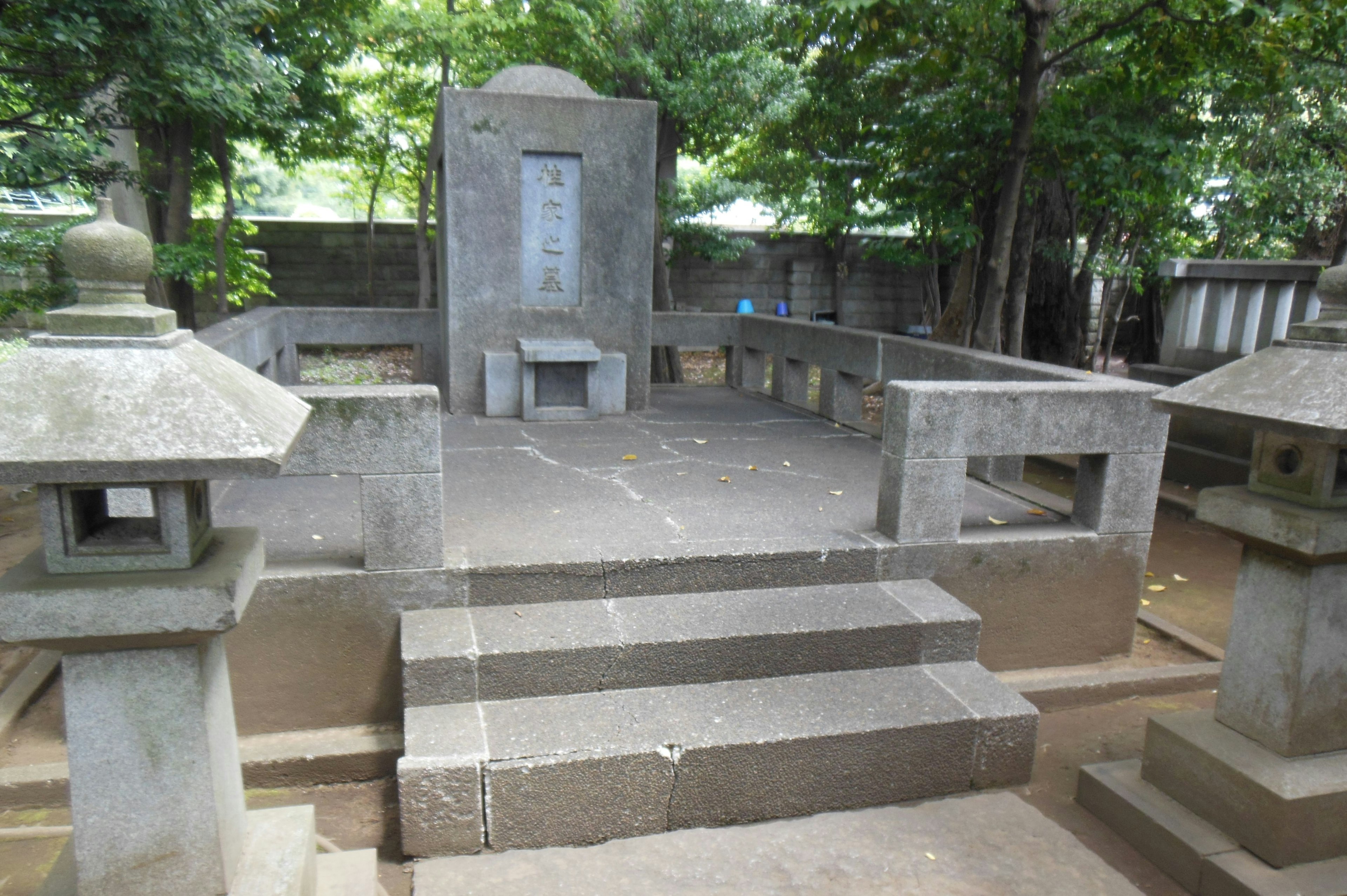 Quiet stone monument with surrounding lanterns in a cemetery