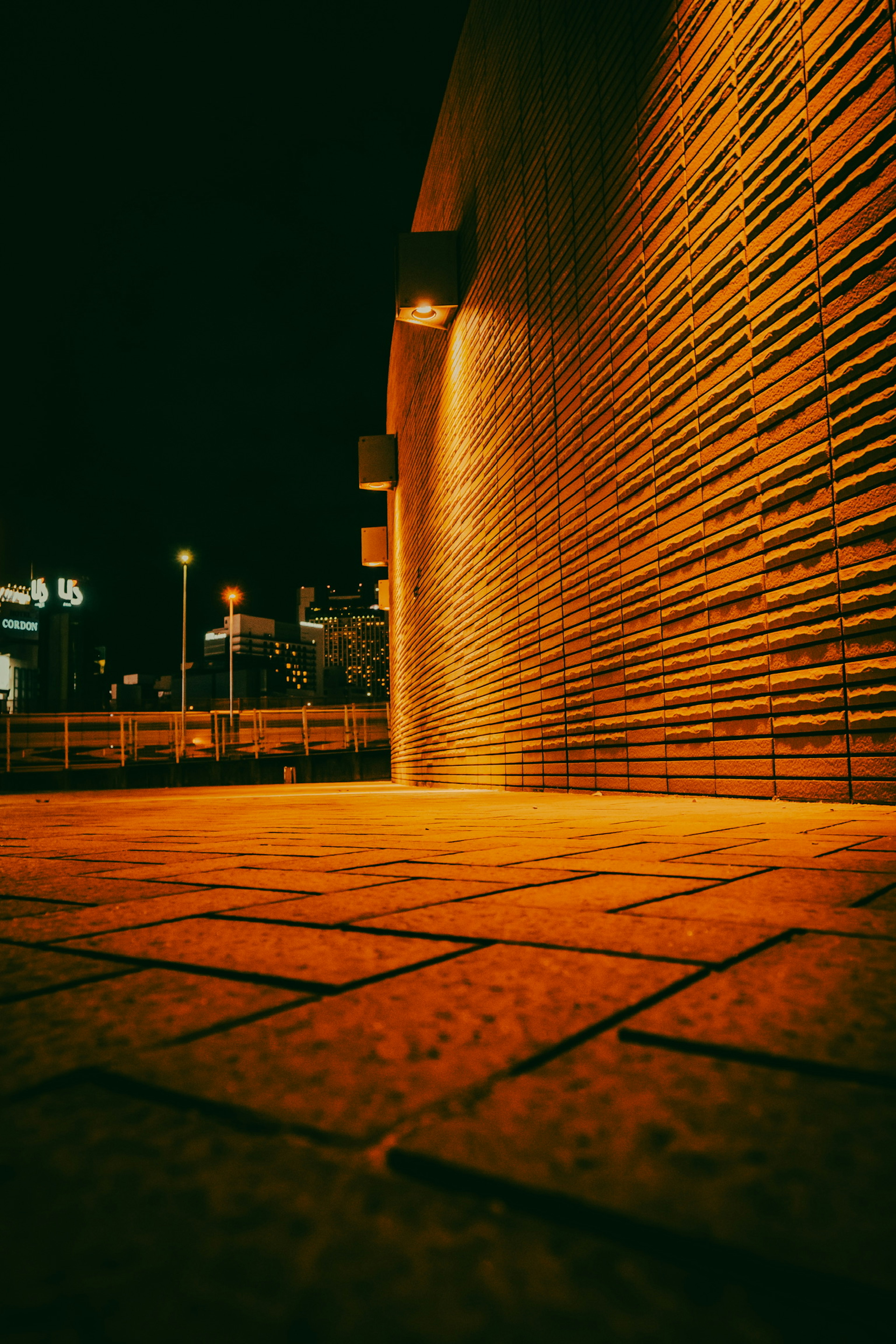 Escena nocturna de una pared de ladrillo iluminada por luces cálidas