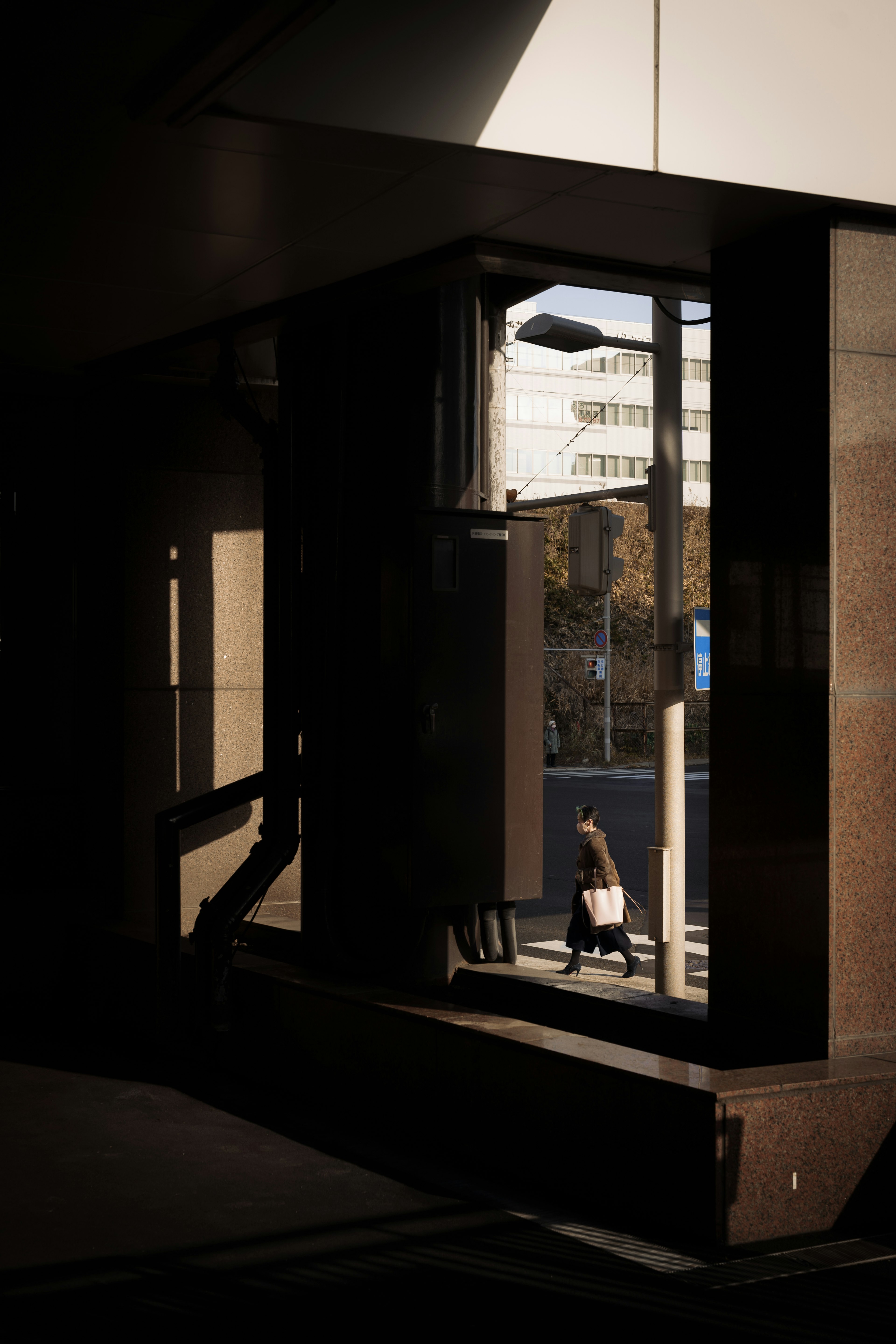 Una silhouette di una persona che cammina attraverso un corridoio scuro con riflessi di edifici