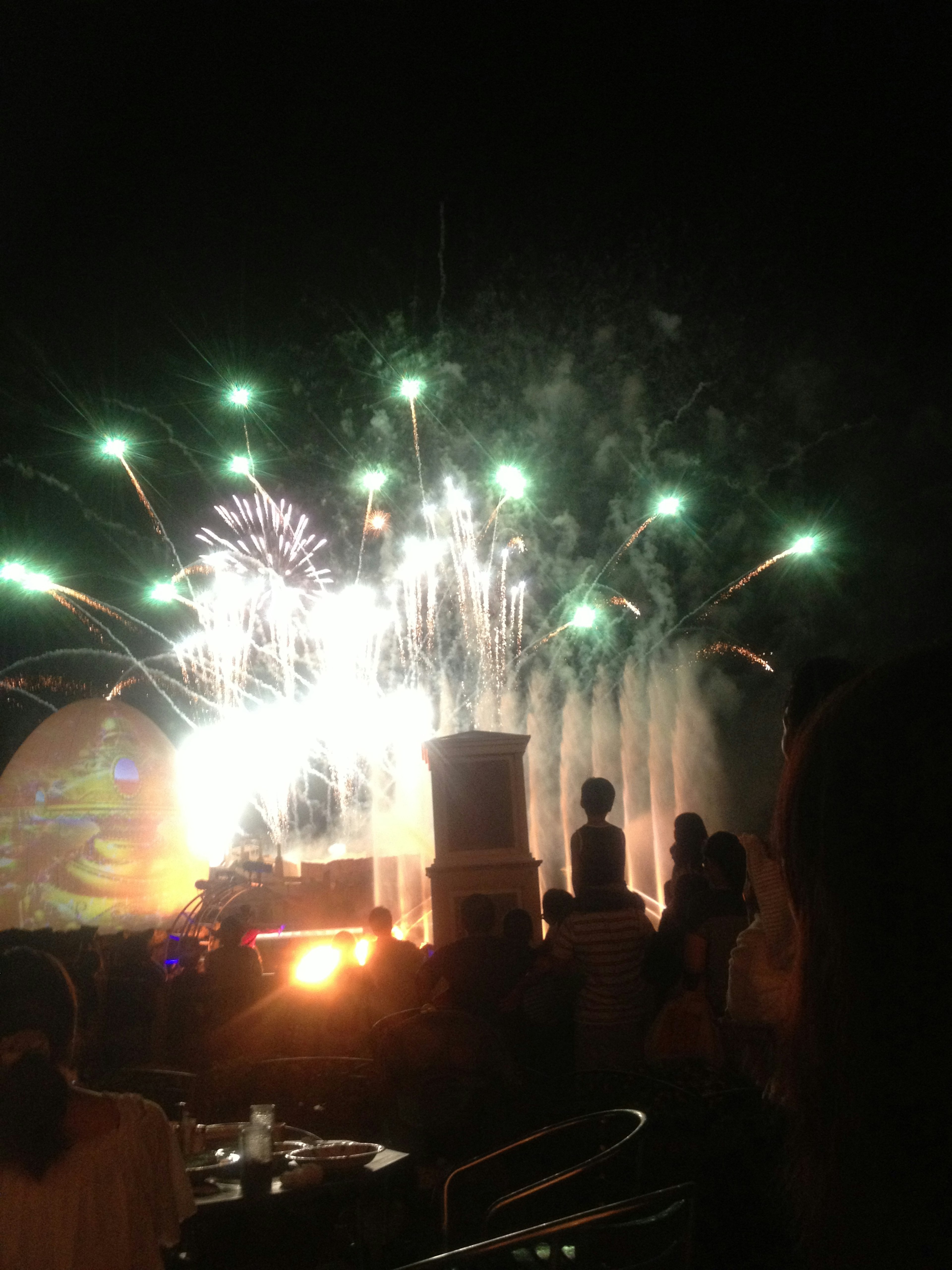 Personas disfrutando de los fuegos artificiales y el espectáculo de fuentes en el cielo nocturno