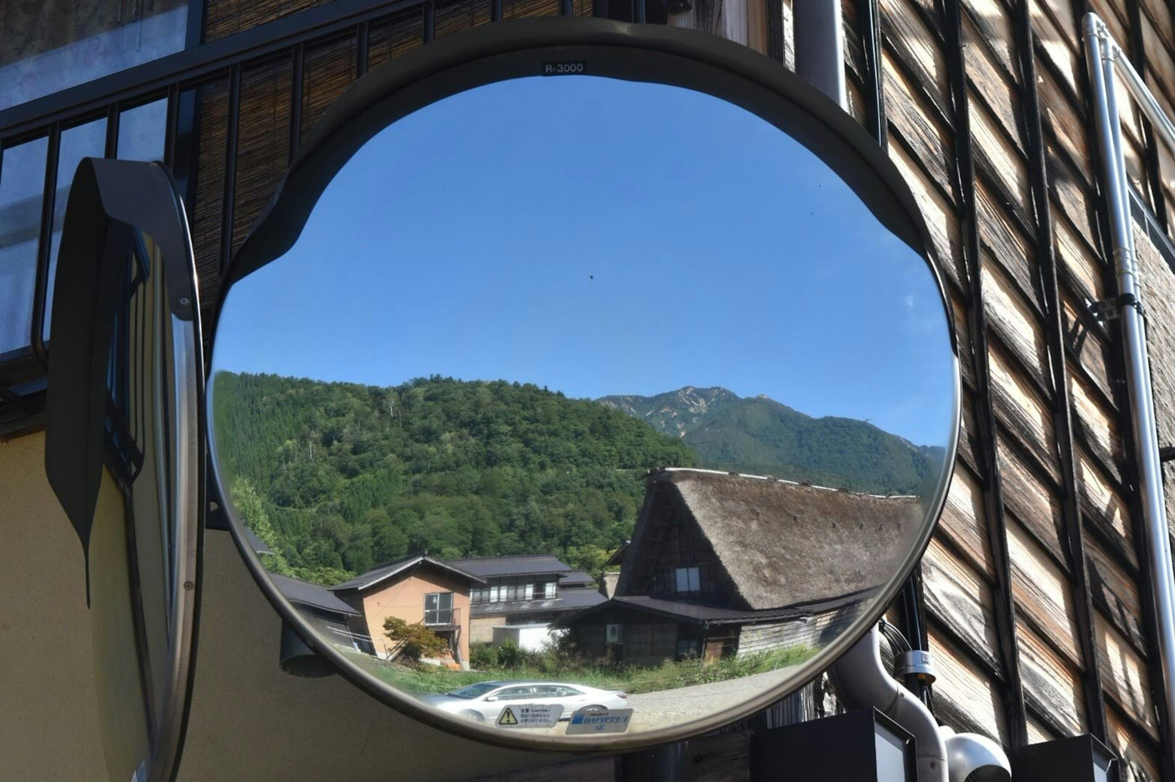 Grand miroir reflétant des montagnes vertes et des maisons