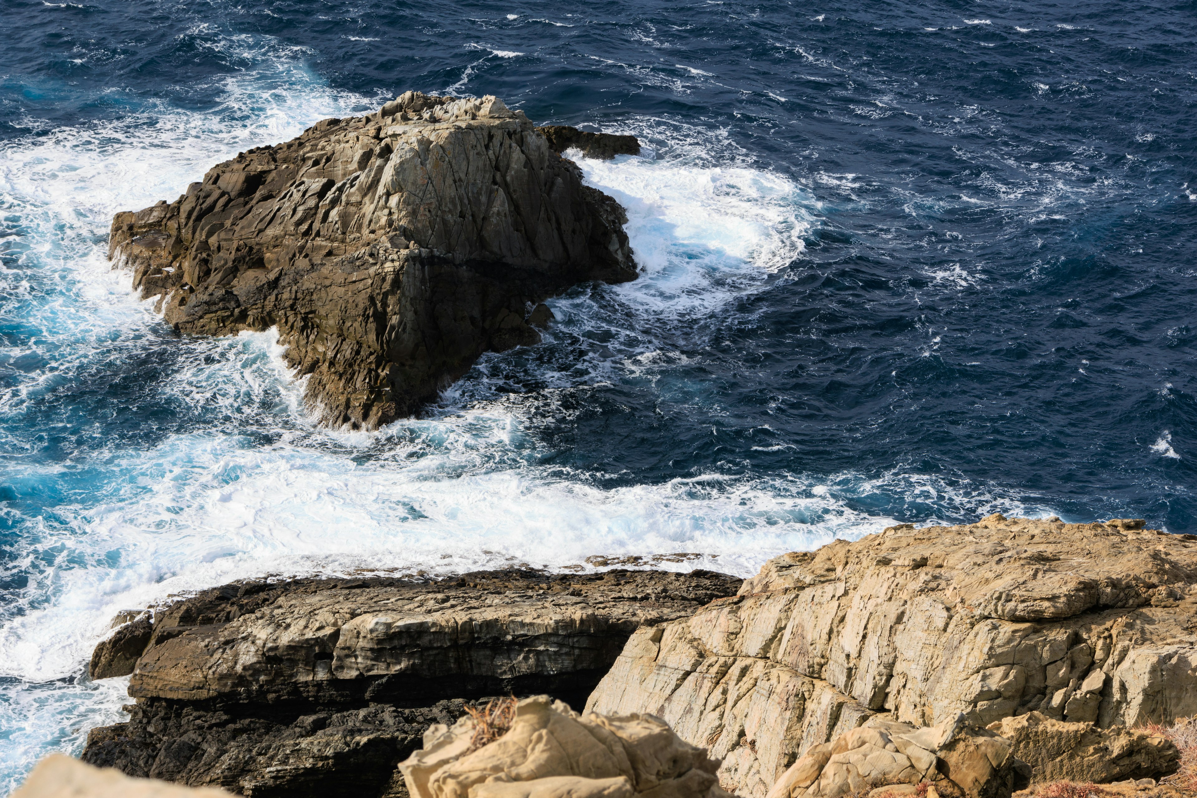 Scena costiera con oceano blu e formazioni rocciose onde che si infrangono contro le rocce