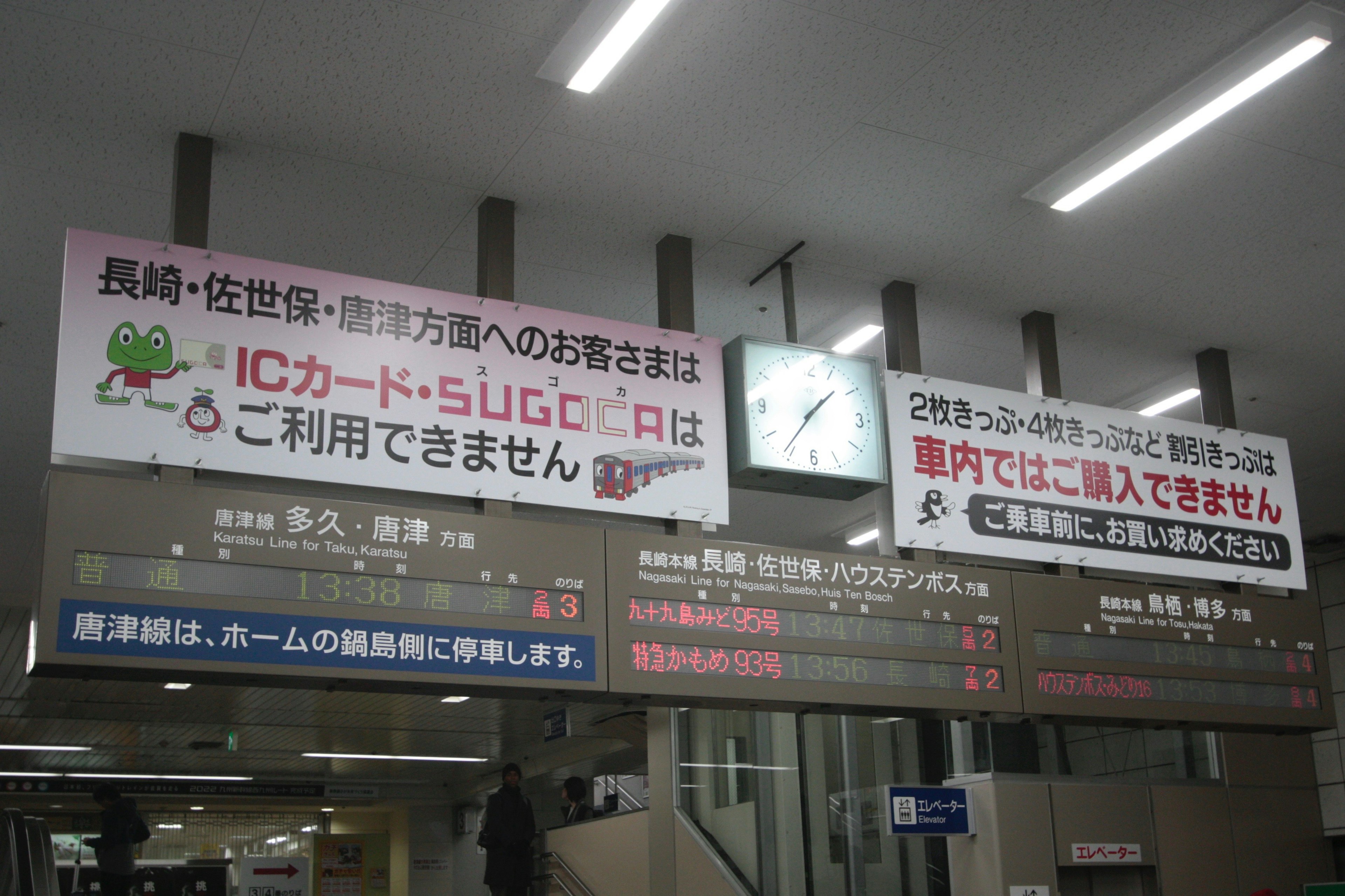 Information signs at a train station with a clock