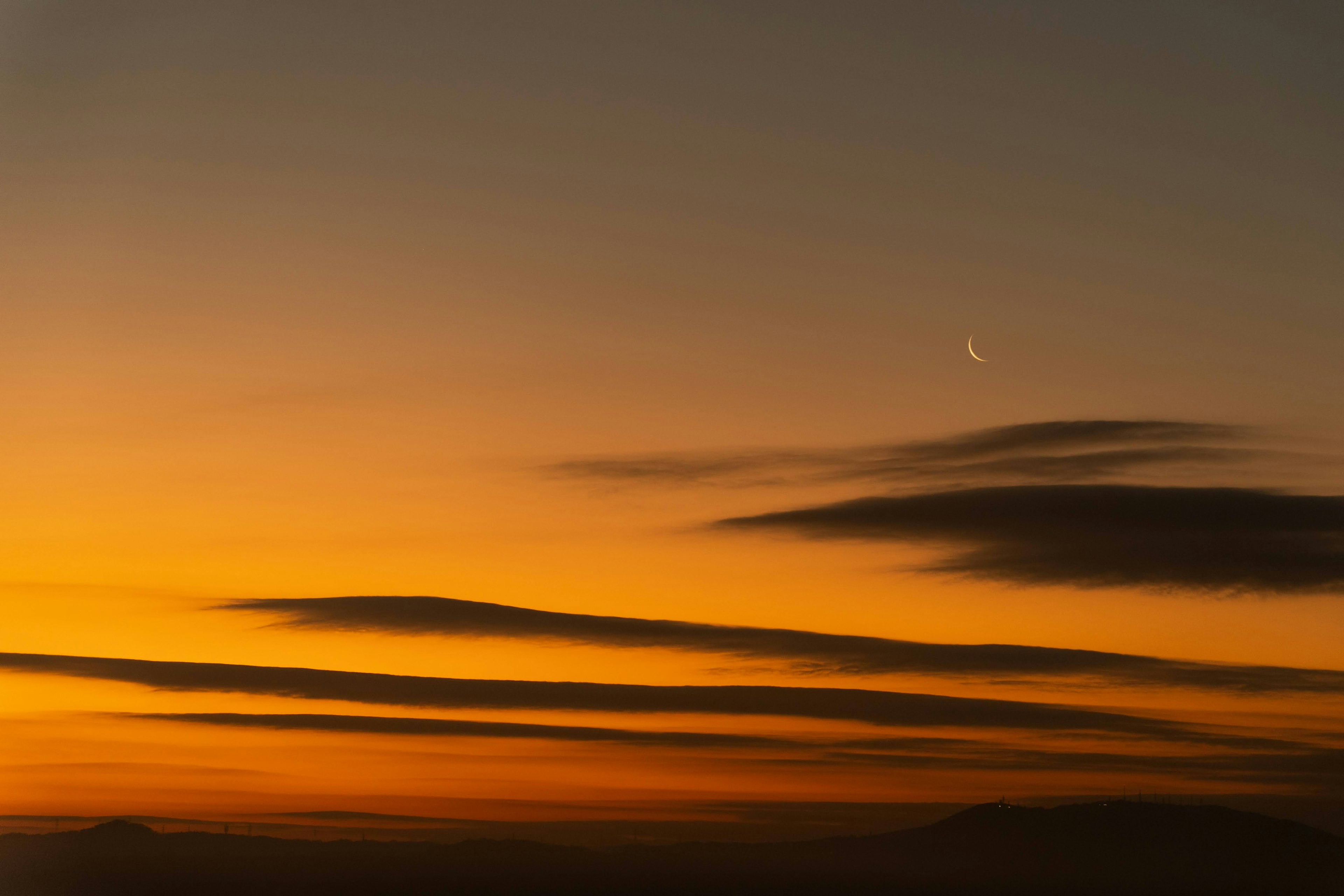 Pemandangan indah langit senja dengan awan tipis dan bulan sabit tipis