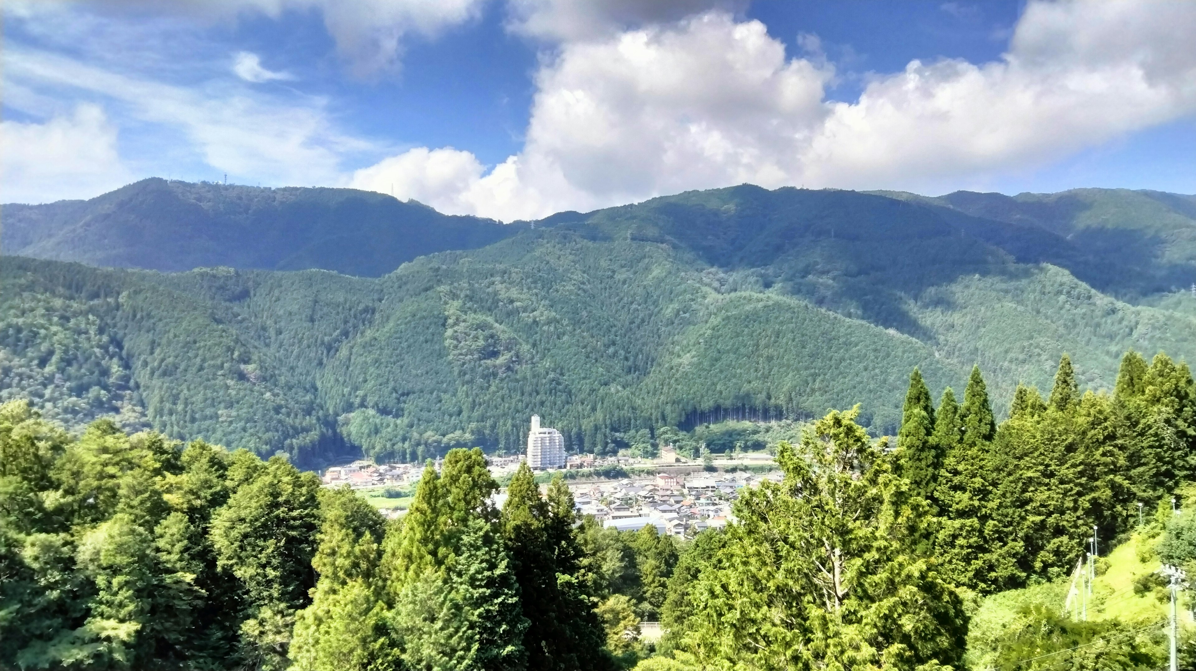 Eine malerische Aussicht auf grüne Berge unter einem blauen Himmel mit einer Stadt im Tal