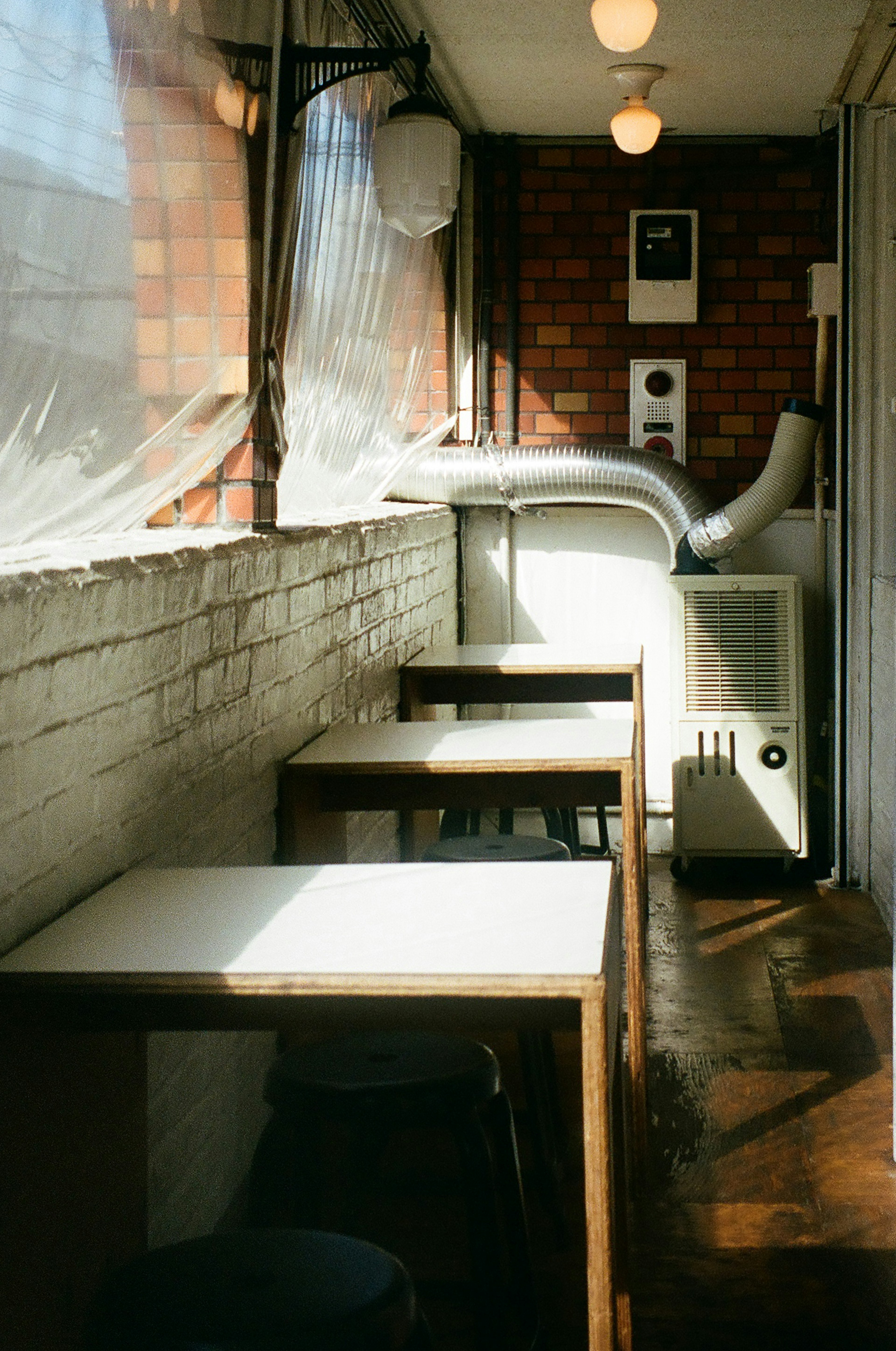 Interior of a cafe with bright windows featuring wooden tables and chairs warm color tones