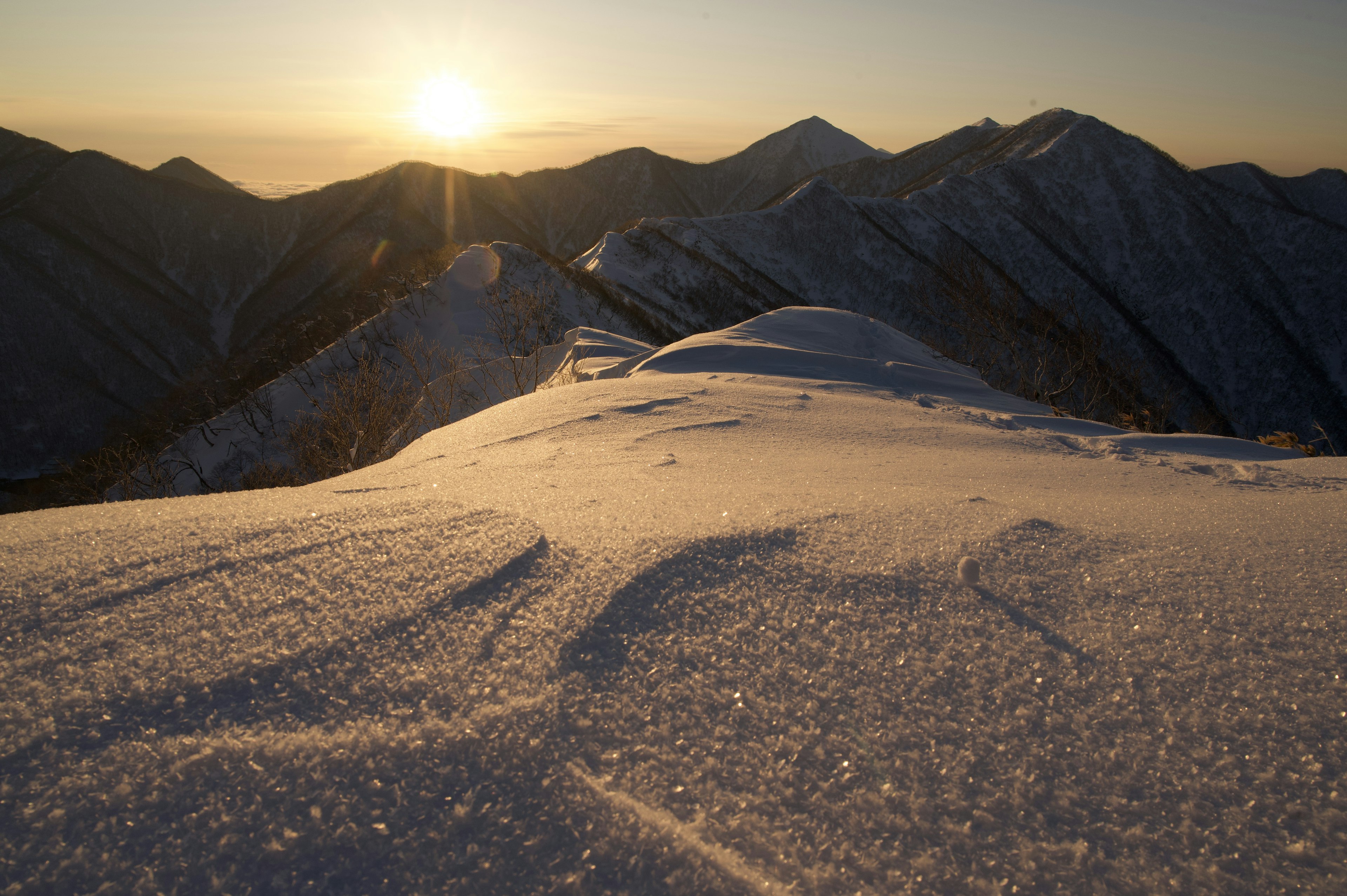 Paesaggio montano innevato con sole nascente