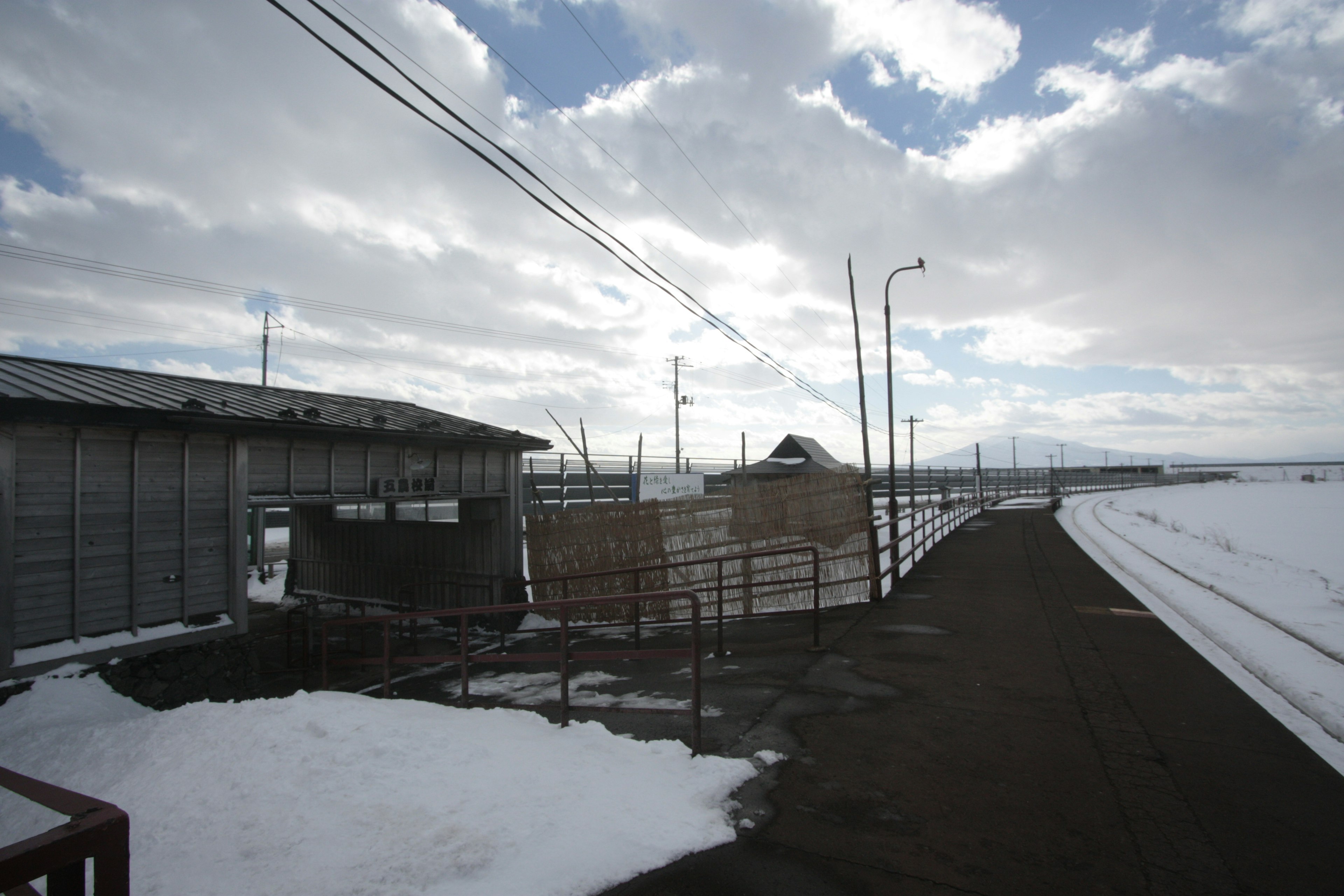 A snowy landscape featuring a pathway and the exterior of a factory