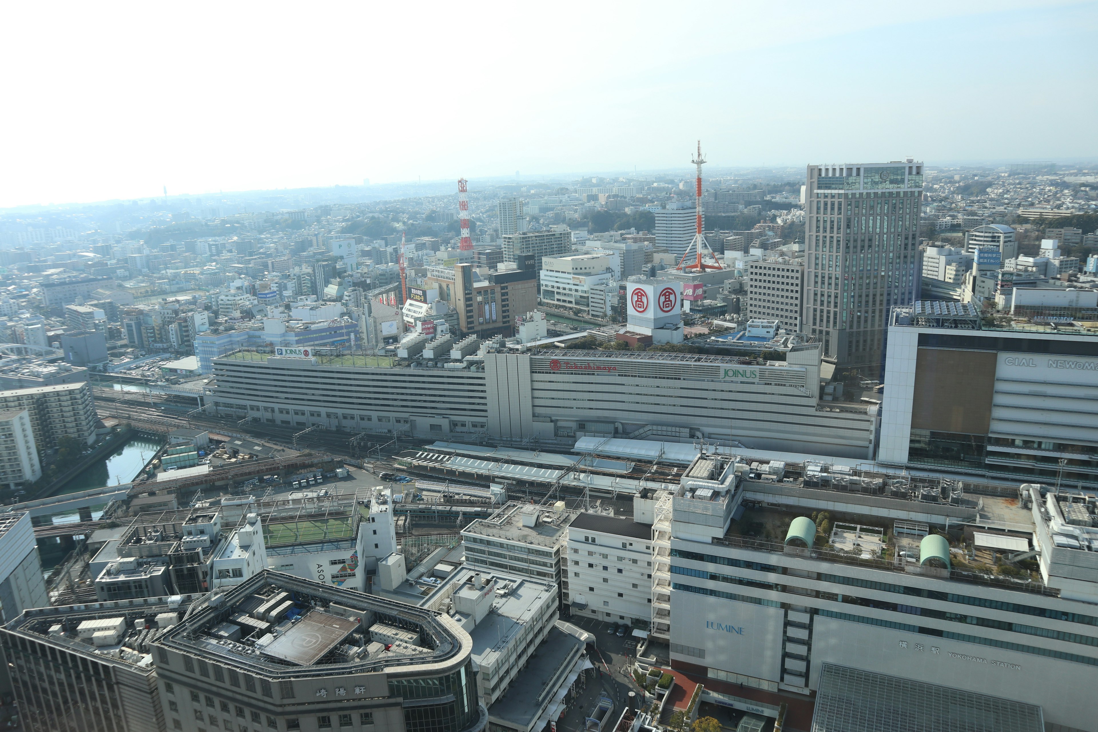 Panoramic view of a cityscape from a high-rise building featuring various buildings and rooftops