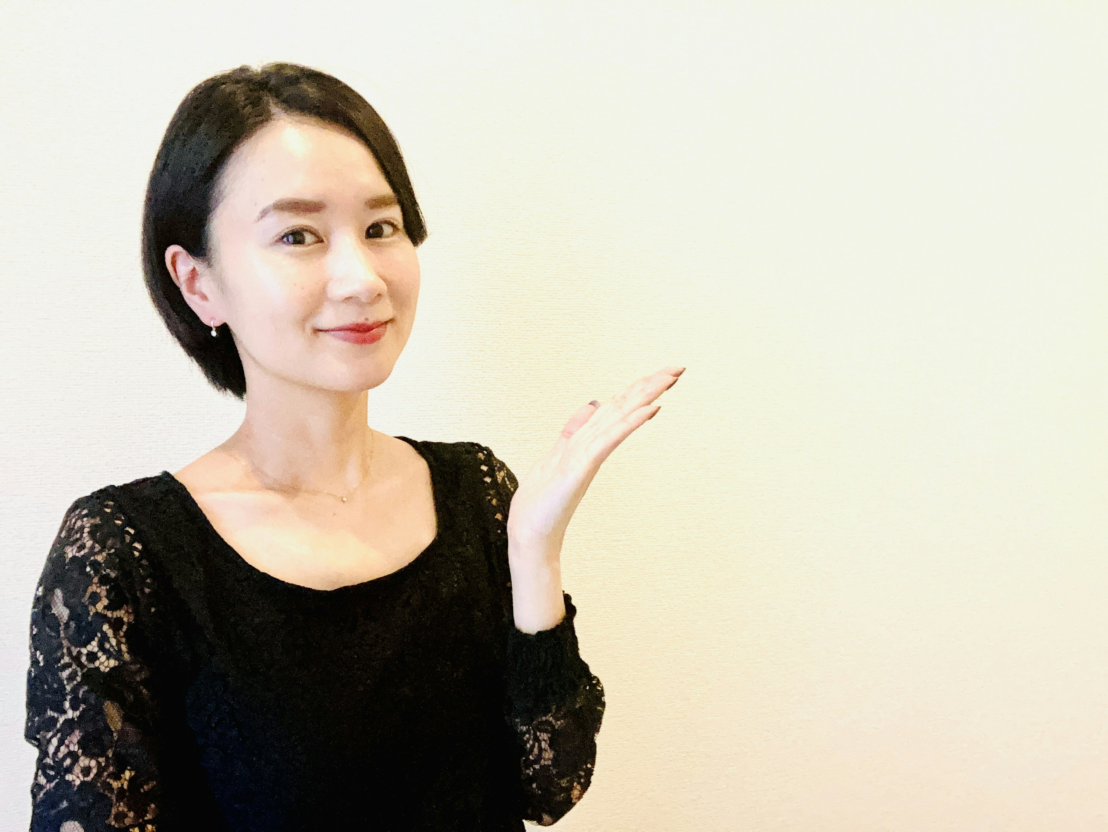 A woman in a black dress smiling and gesturing with her hand