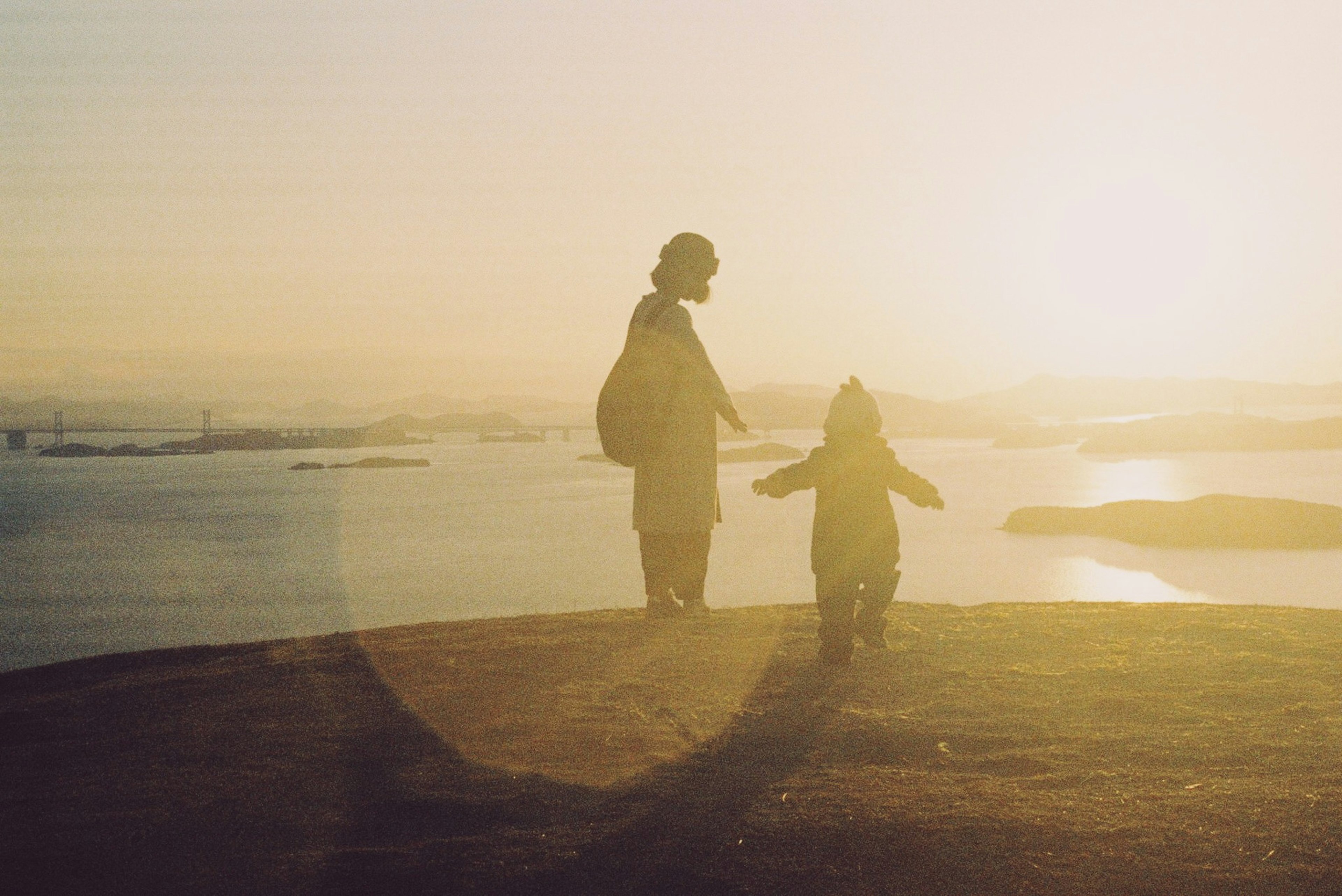 Silhouette of a parent and child against a sunset