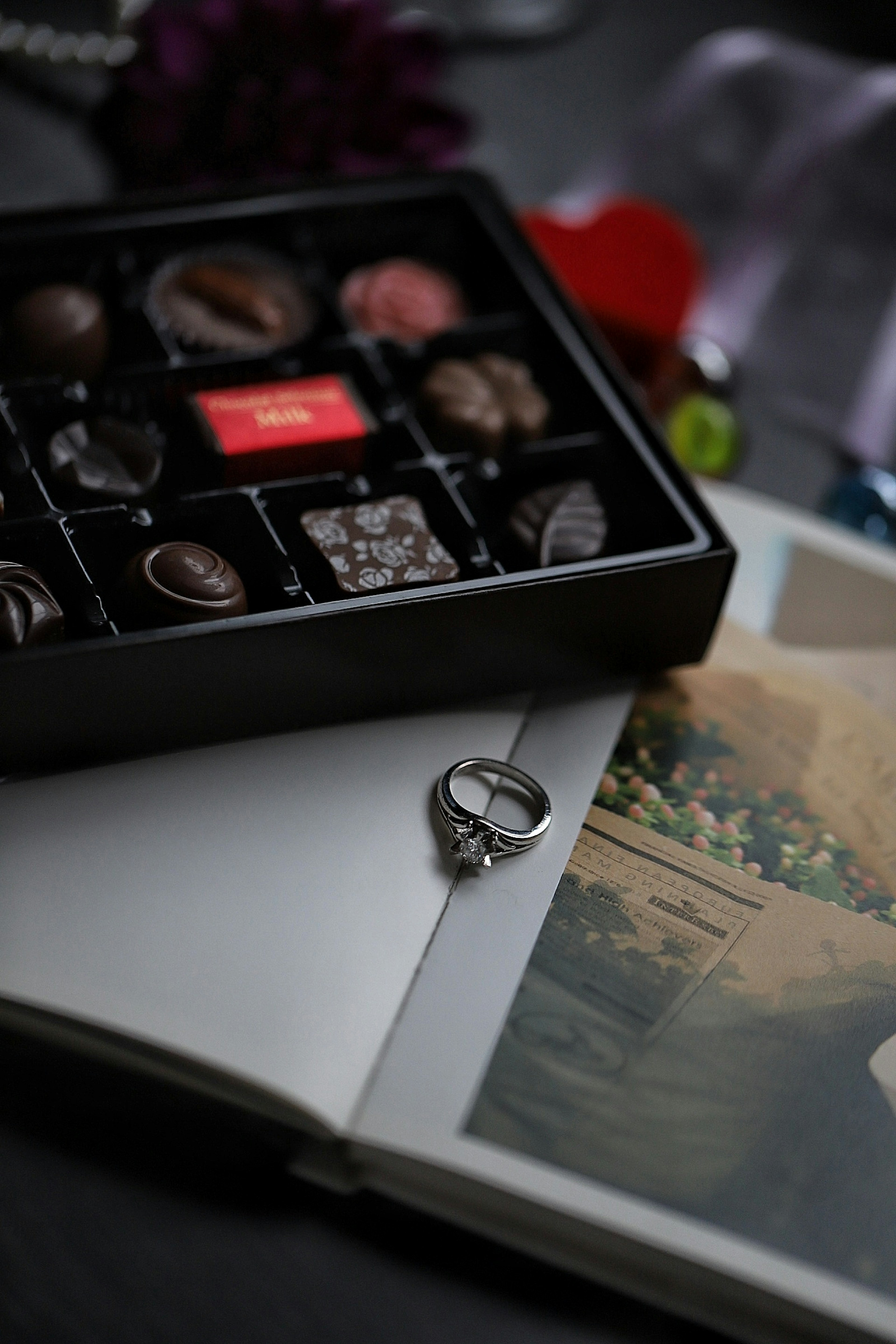 Libro abierto con un anillo de boda y una caja de chocolates