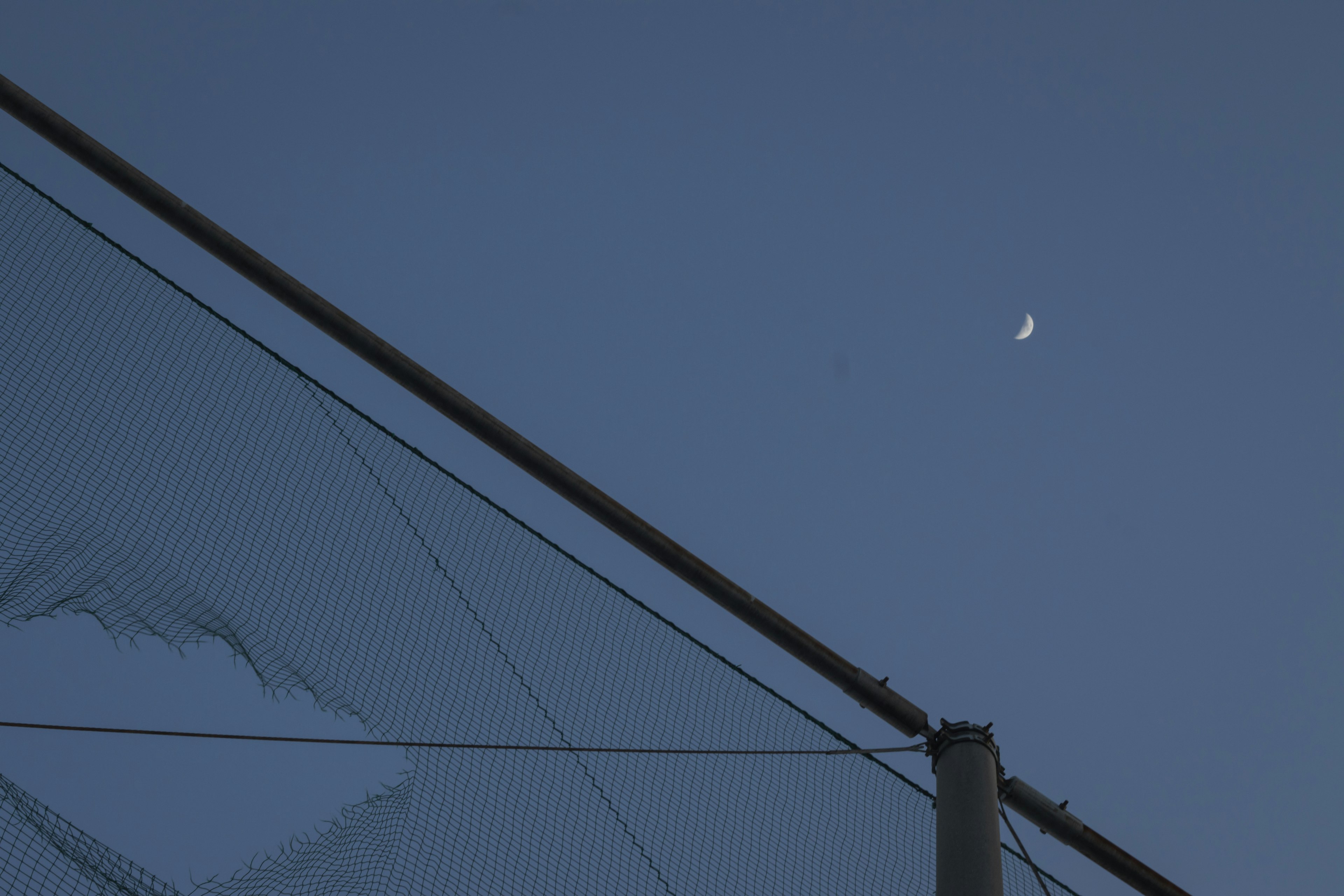 Luna creciente en el cielo nocturno con silueta de líneas eléctricas