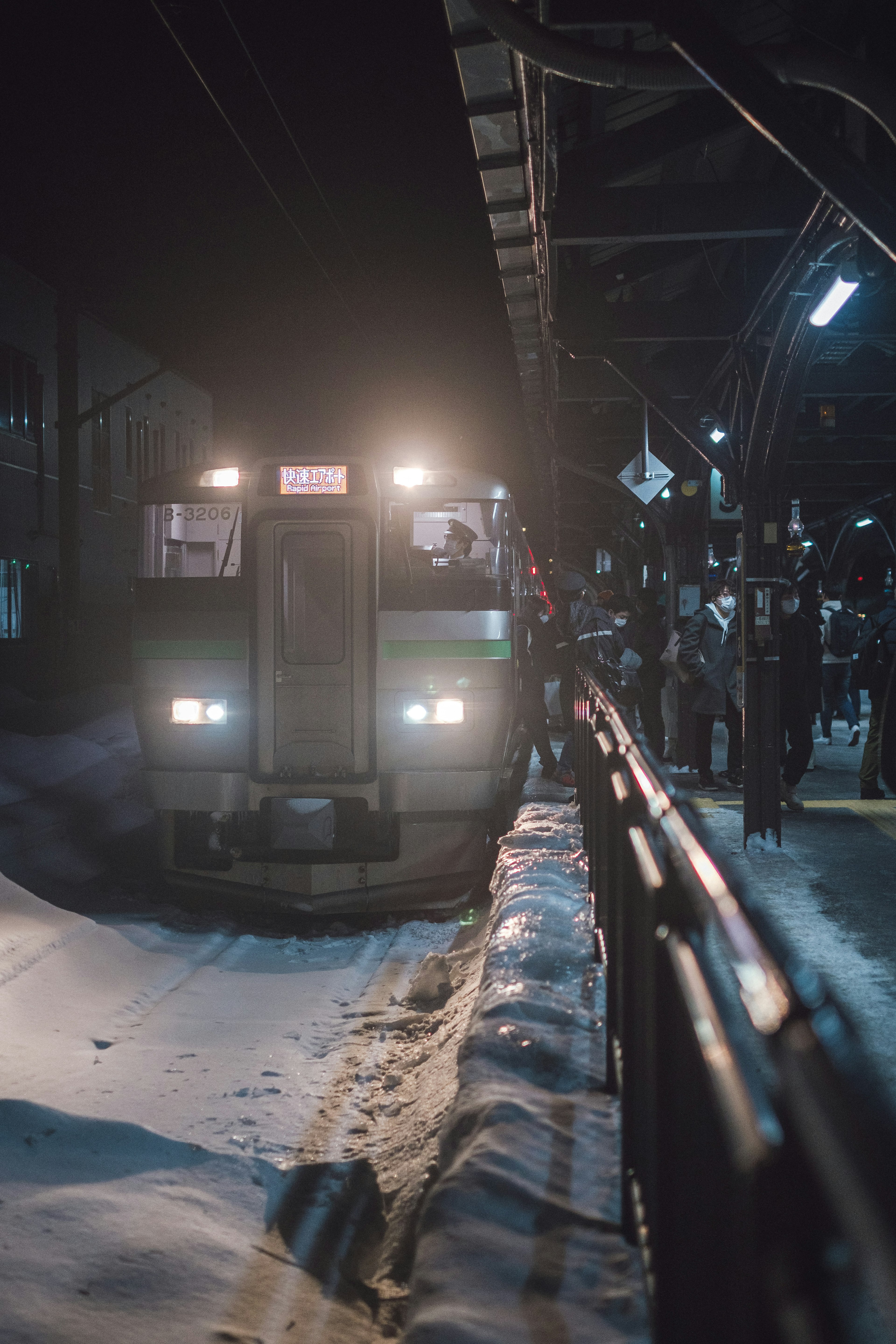 Treno in arrivo a una stazione di notte con passeggeri