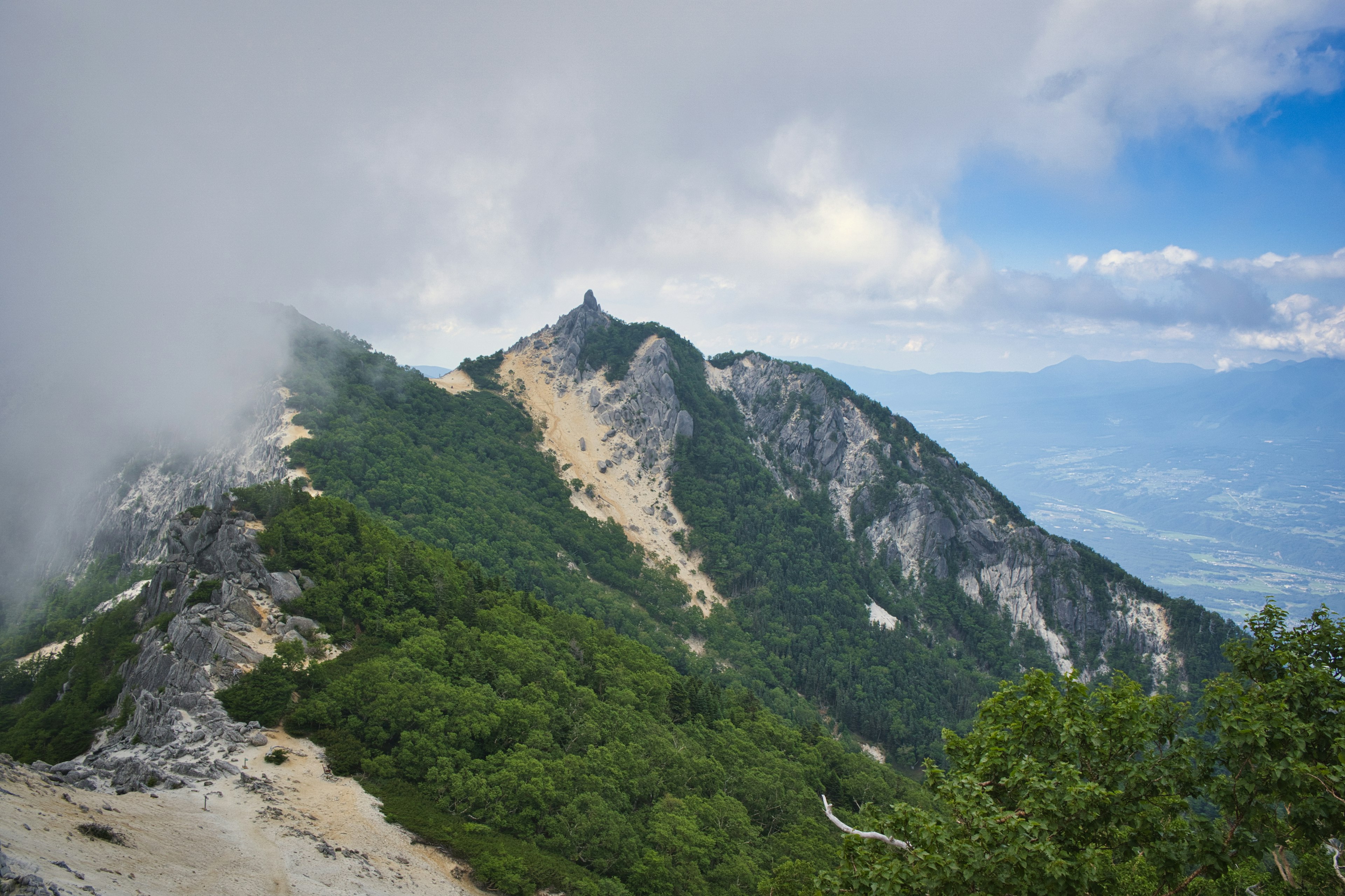 Mountain landscape with blue sky and clouds green forest and rocky terrain