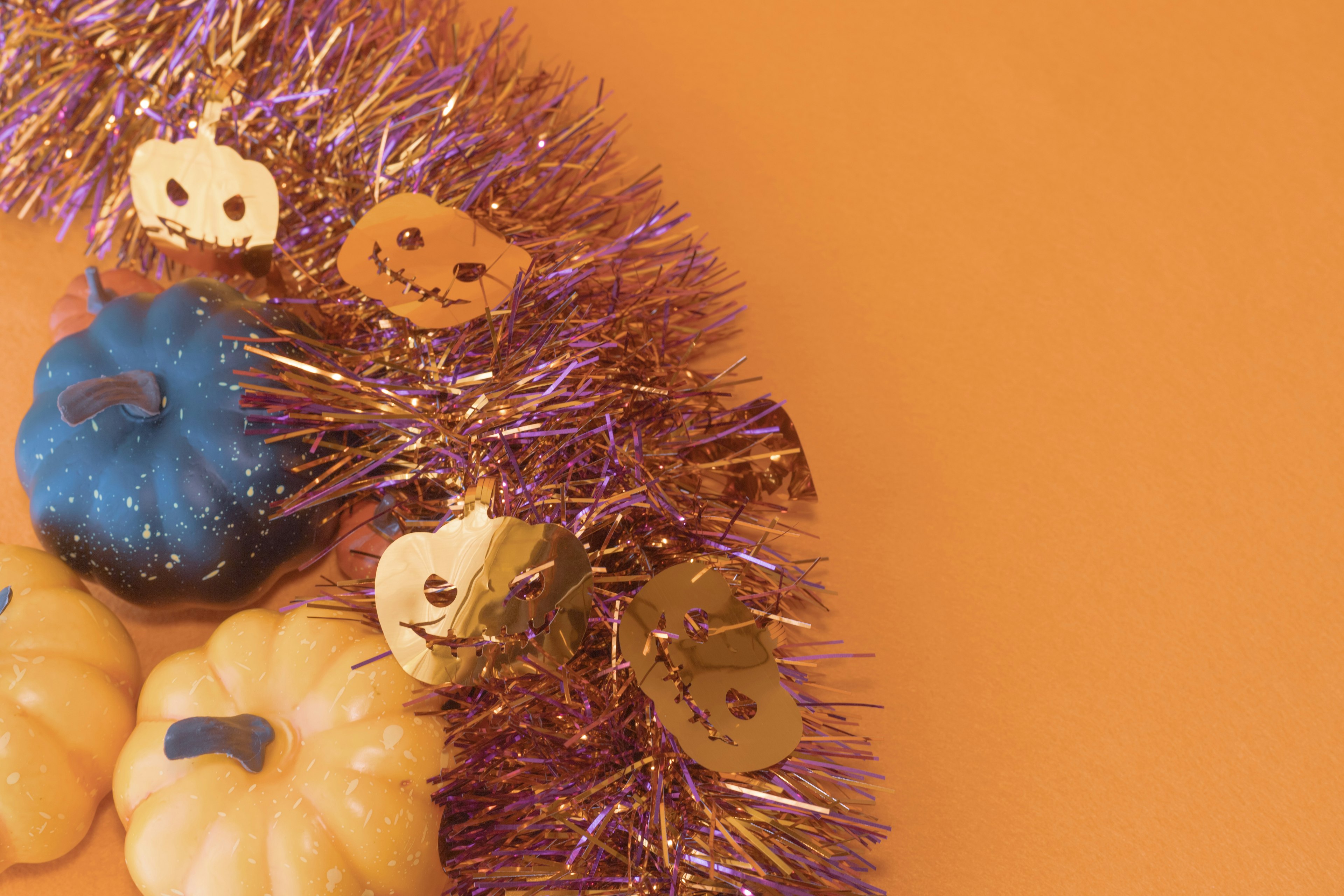 Decoración de calabazas coloridas y purpurina morada sobre un fondo naranja